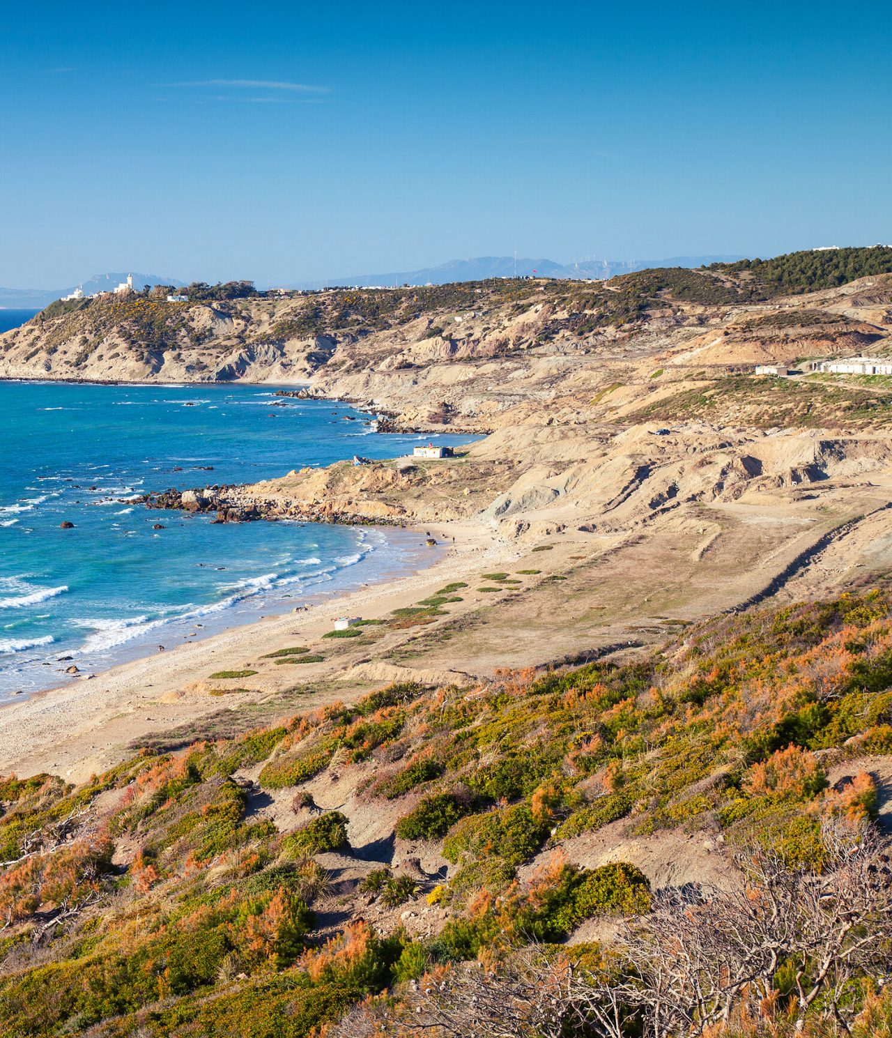 Vista desde arriba de las playas de Tánger, donde se ven las olas del mar y todo el entorno verde alrededor de la playa