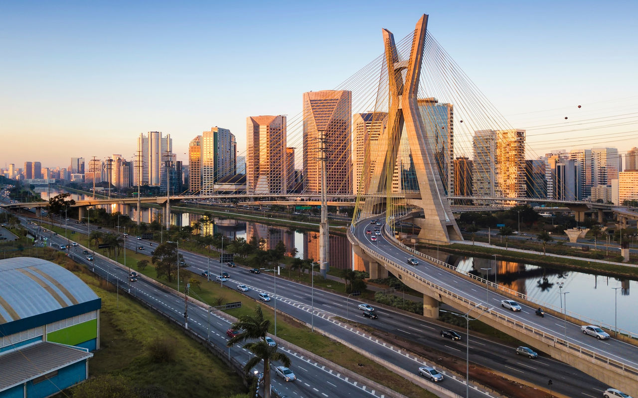 Paisagem urbana de São Paulo com a Ponte Estaida cortando o Rio Pinheiros, sob um céu azul