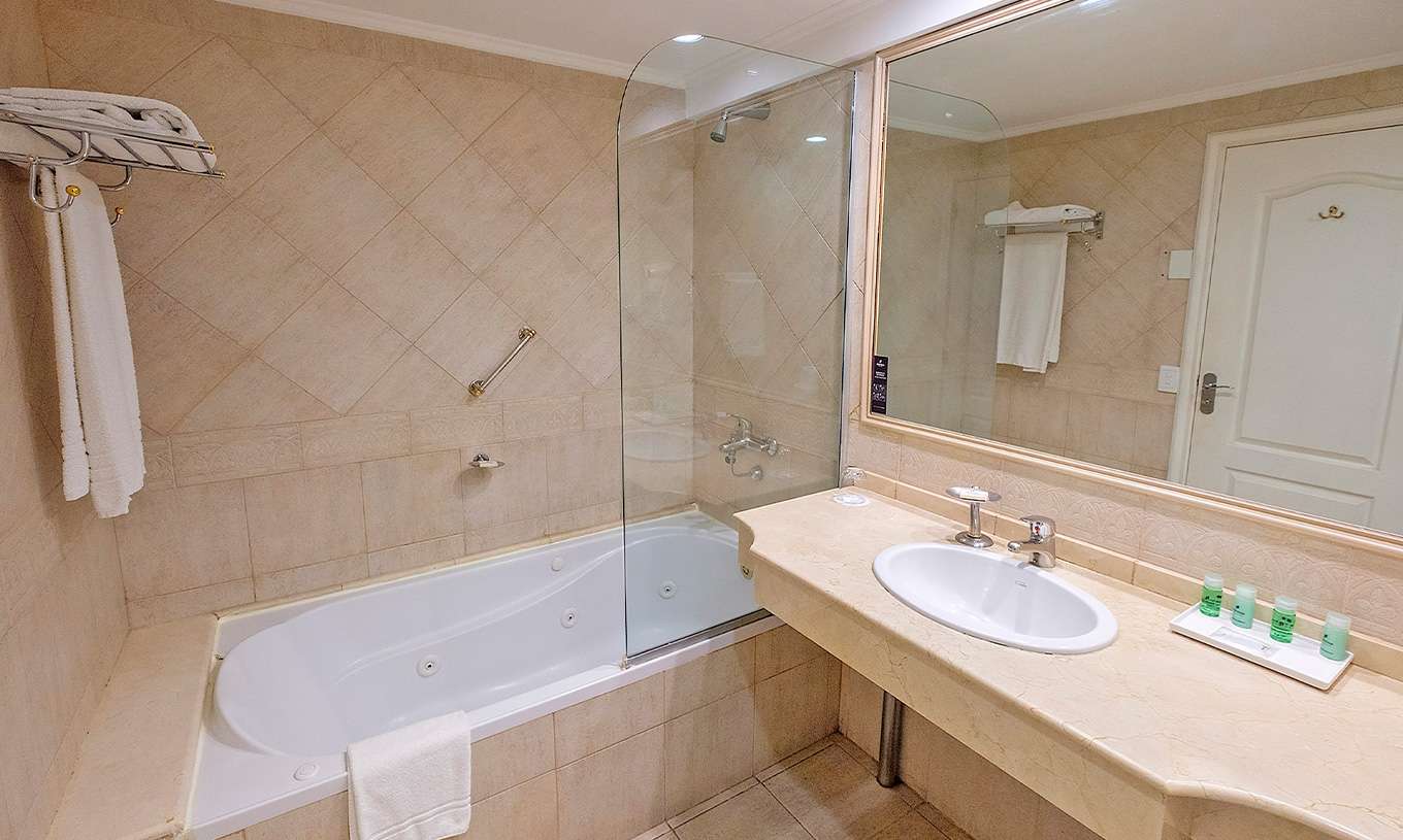 Das Twin Executive Zimmer im Pestana Buenos Aires hat ein Bad mit Waschbecken, Spiegel und Badewanne mit Dusche
