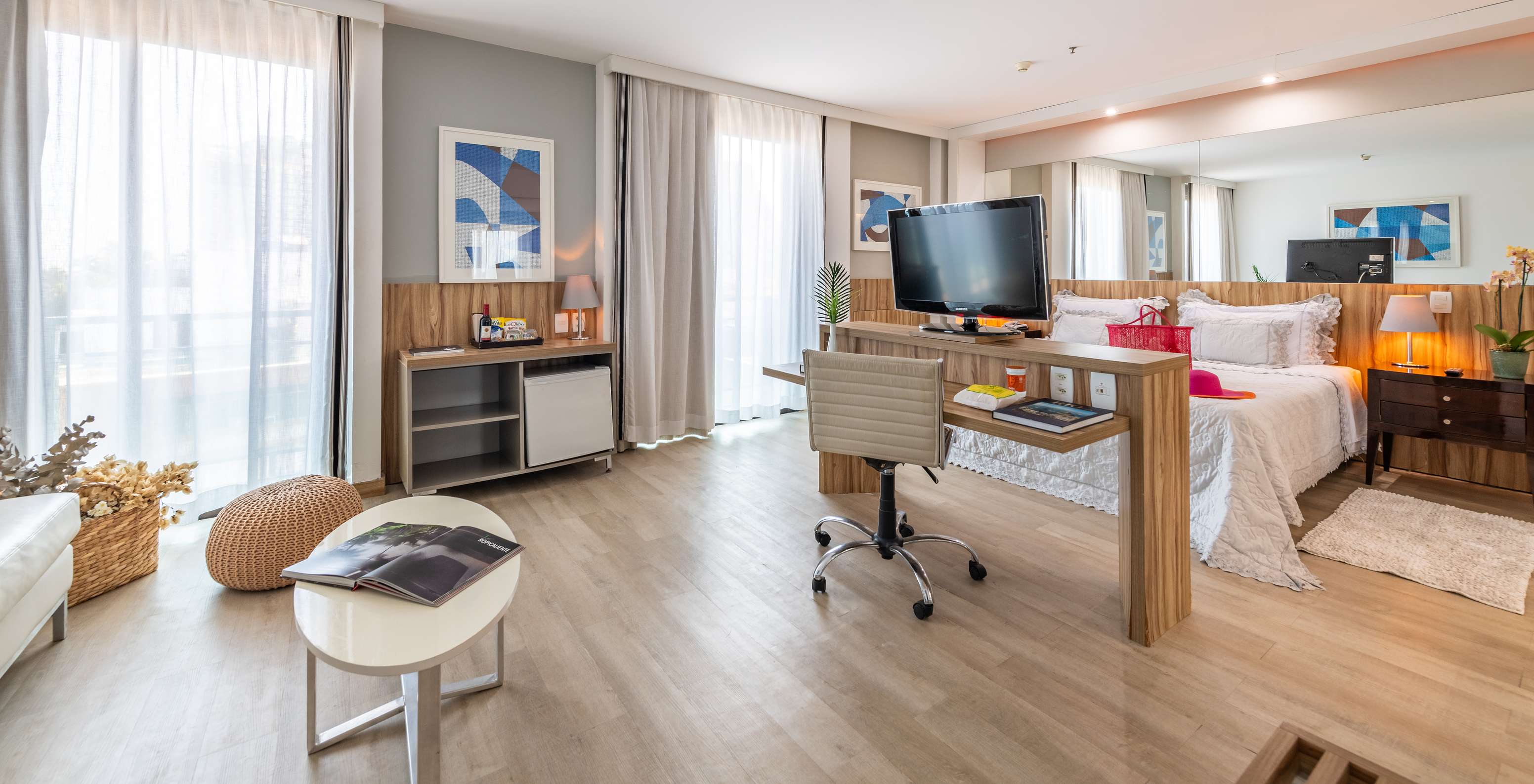 Die Junior Suite mit seitlichem Meerblick hat ein Doppelbett, einen Schreibtisch, Fernseher und zwei Fenster mit Vorhängen 