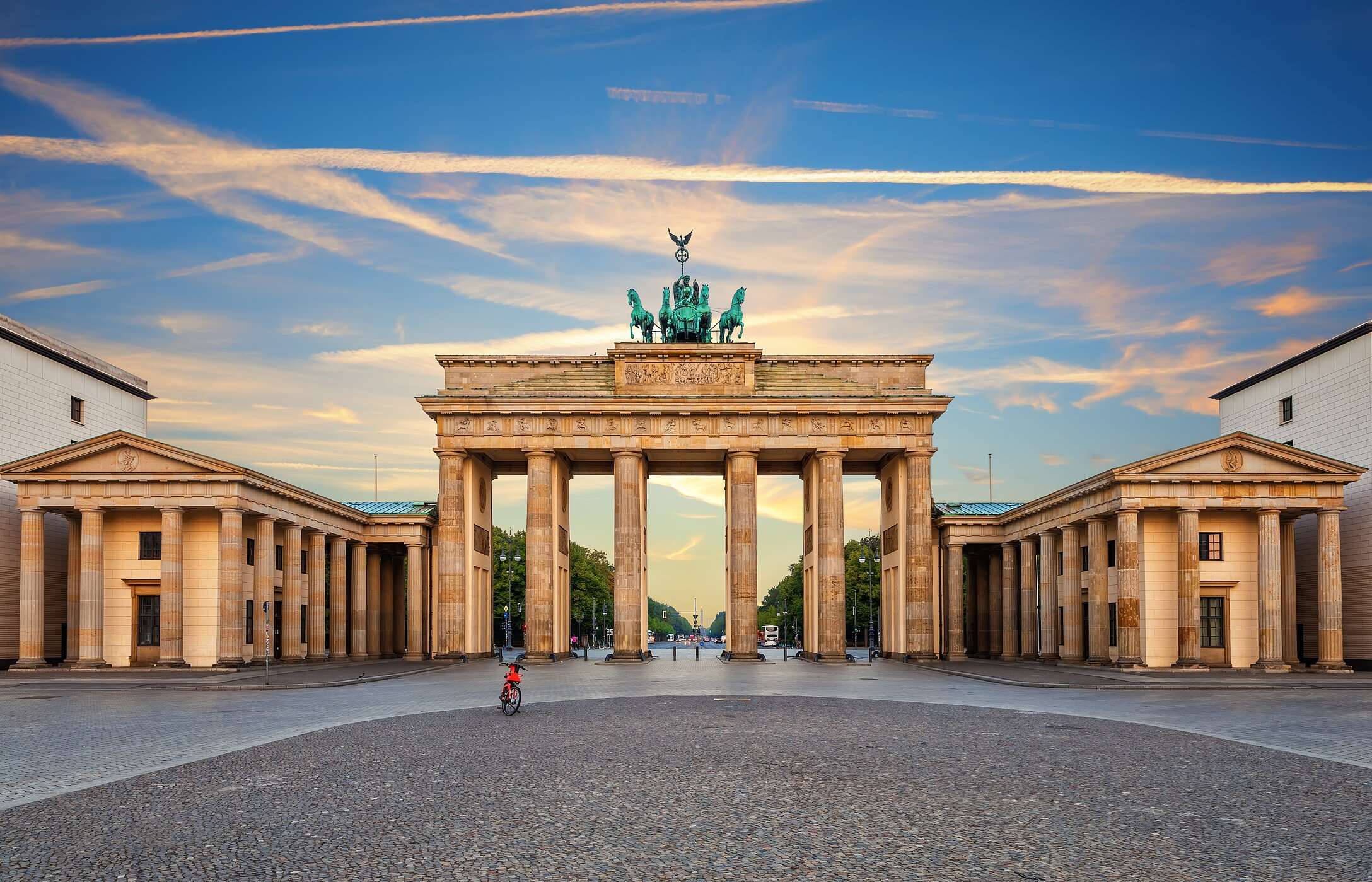 Stadtlandschaft von Berlin, mit dem ikonischen Brandenburger Tor, unter einem blauen Himmel und der Allee Unter den Linden im Hintergrund