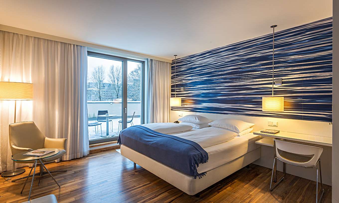 Das Deluxe Zimmer mit Terrasse im Pestana Berlin Tiergarten hat ein Doppelbett, Schreibtisch und einen Sessel