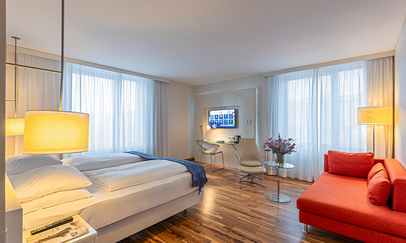 Das Grand Deluxe Zimmer im Pestana Berlin Tiergarten hat ein Doppelbett, Fernseher, Sofa, Sessel und Schreibtisch