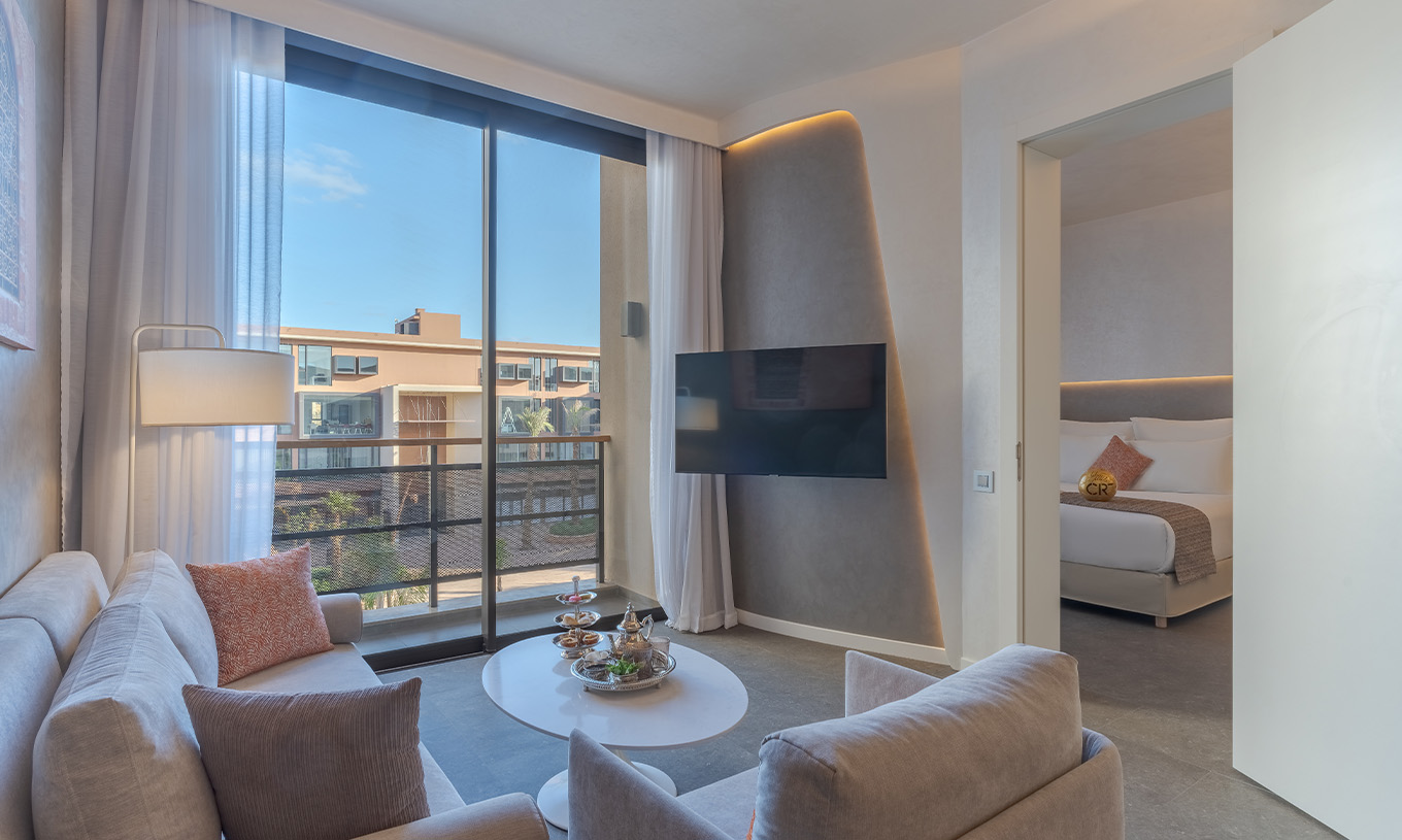 Die CR7 Suite Avenue im Pestana CR7 Marrakeck hat ein Wohnzimmer mit Sofas, Fernseher und Balkon mit Blick auf die M Avenue