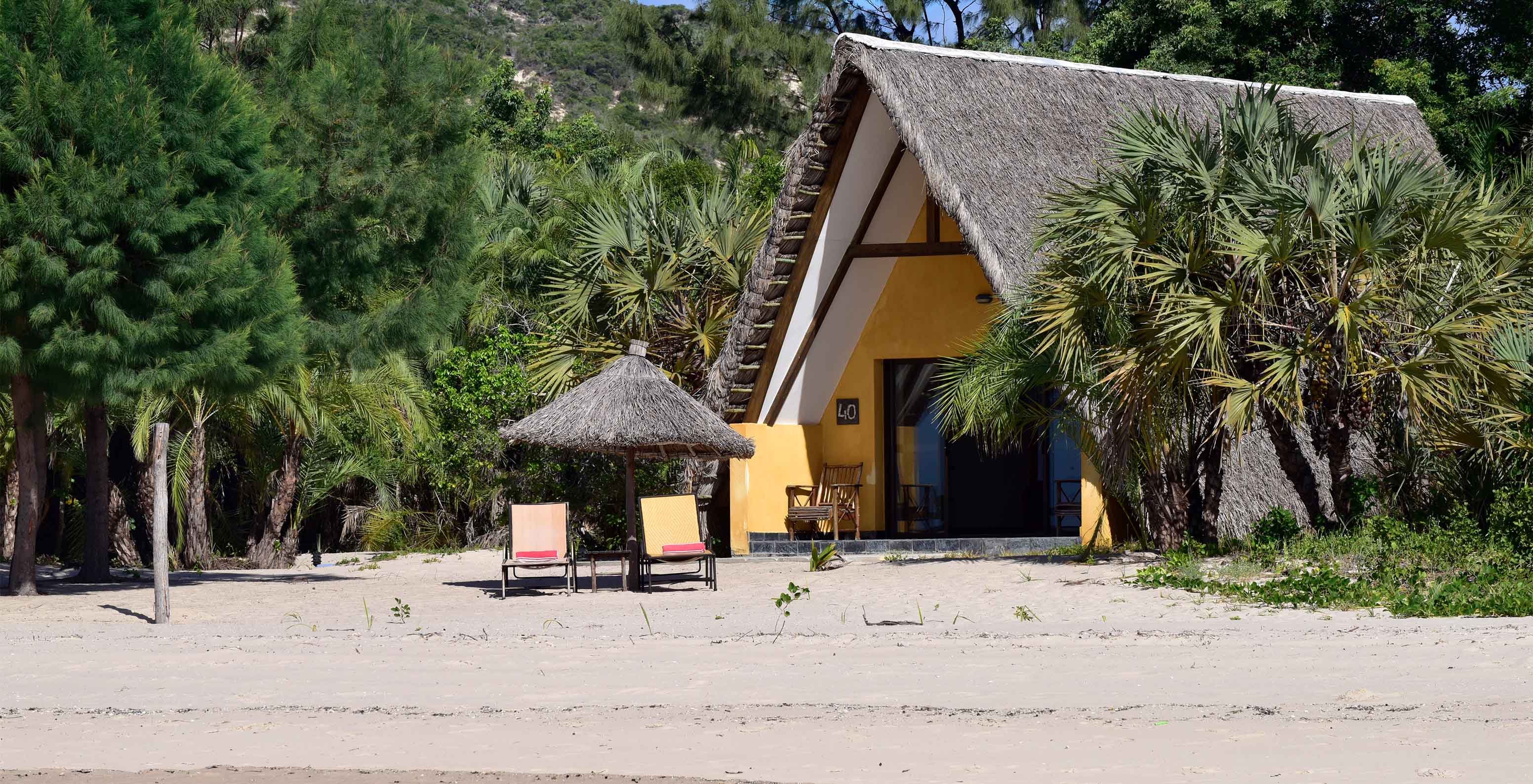 Die Bungalow Suite T2 im Pestana Bazaruto Lodge ist ein Häuschen mit einem Strohdach am Strand in üppiger Natur