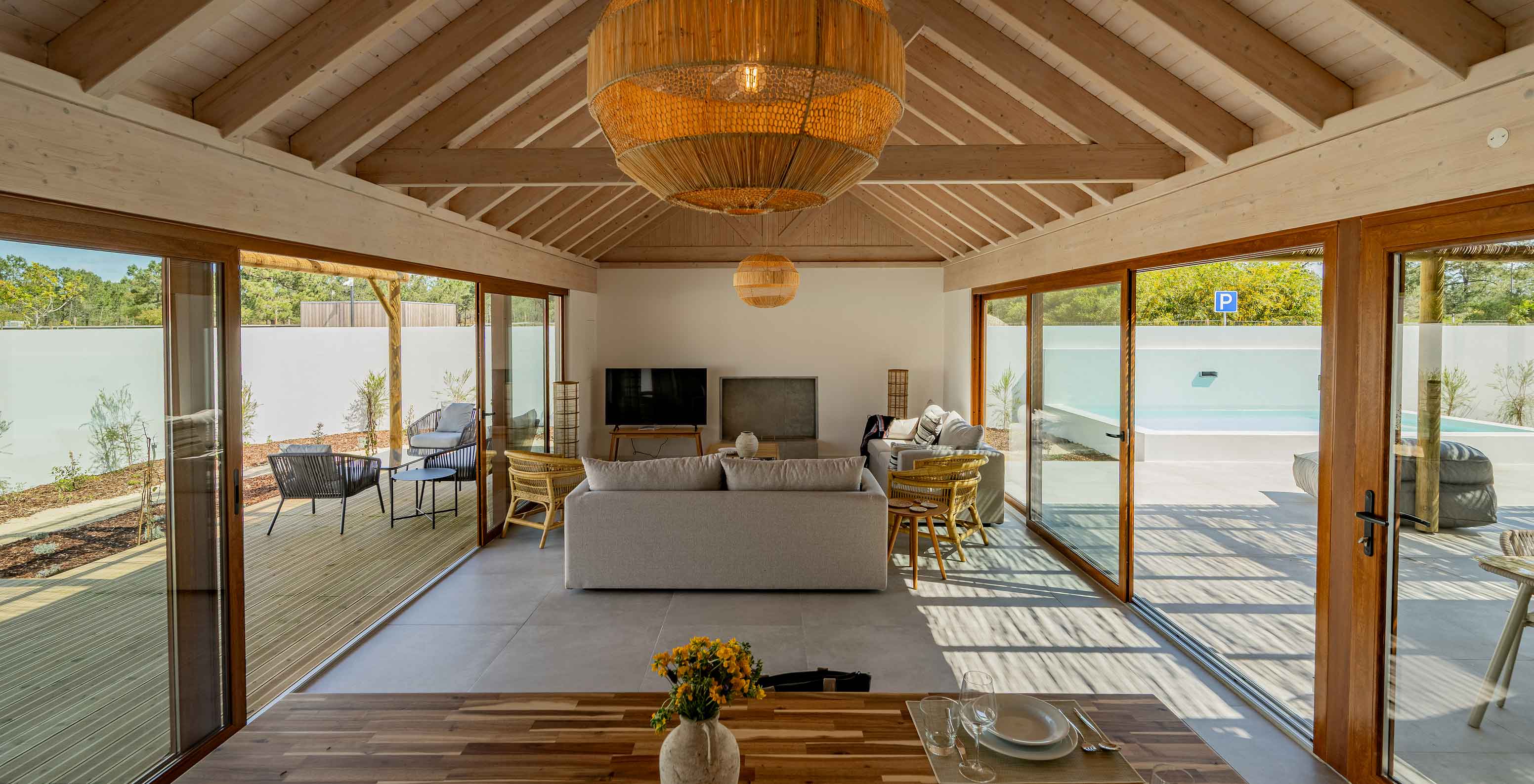 Die Premium Green Villa im Pestana Comporta Village Residences hat ein Wohnzimmer mit großen Fenstern und einem Tisch