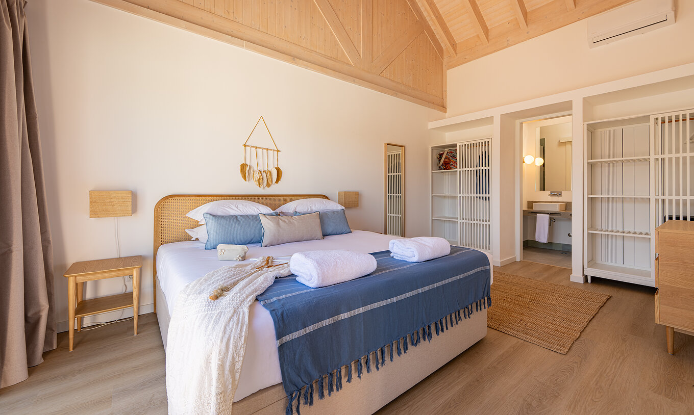Die Premium Villa im Pestana Comporta Village Residences hat ein Schlafzimmer mit Doppelbett und mehreren blauen Kissen