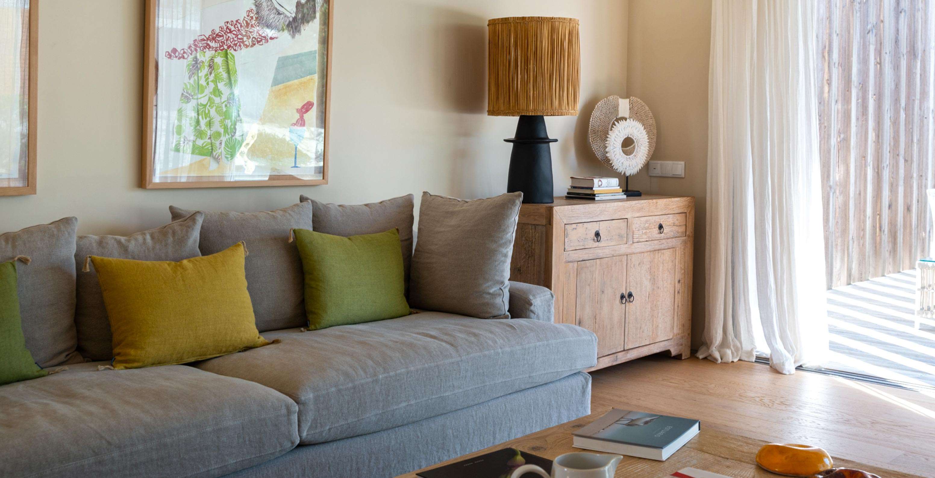 Die exklusive Villa mit Pool im Pestana Tróia Eco Resort hat ein Wohnzimmer mit grauem Sofa und großem Fenster mit Vorhängen