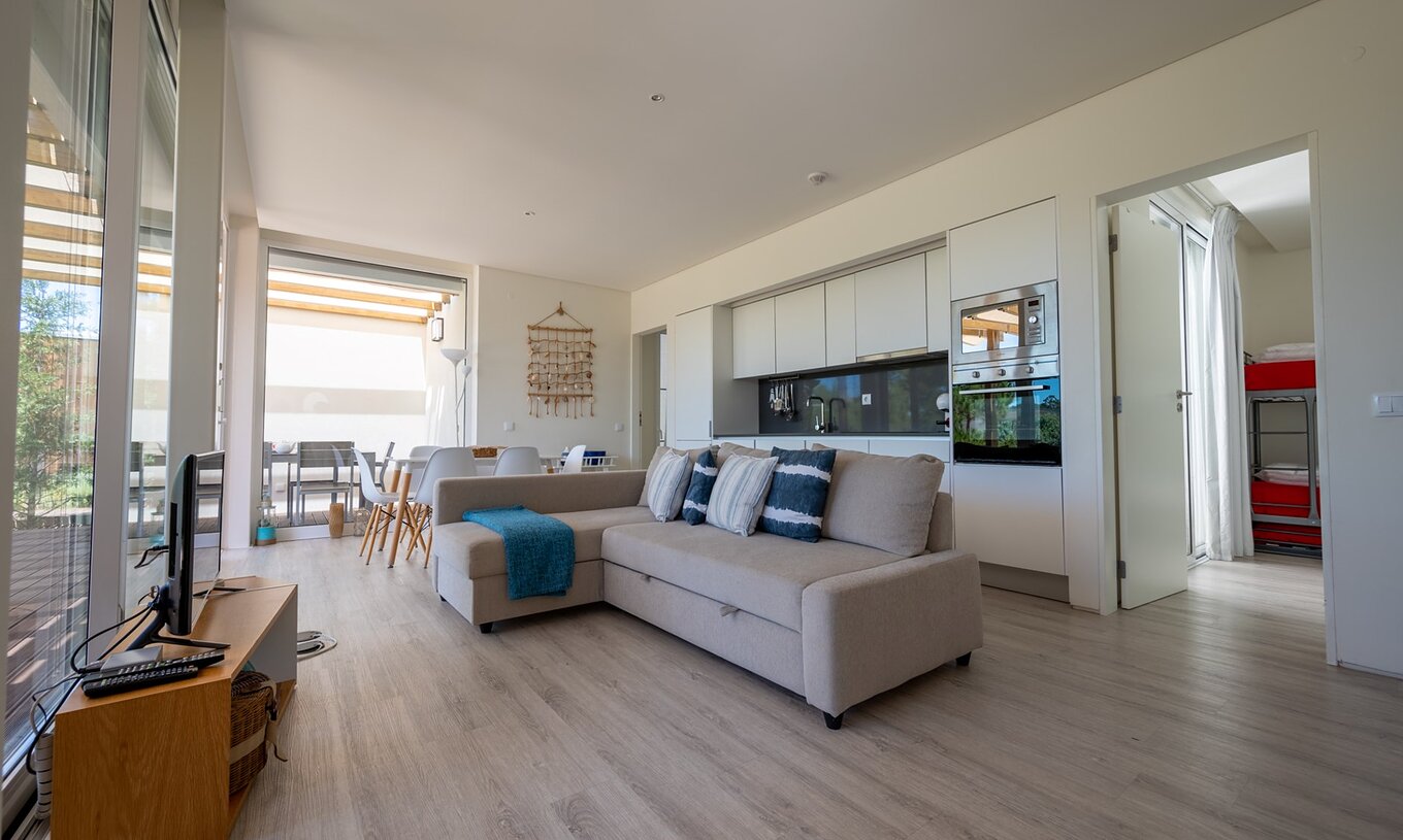 Die Green Villa mit privatem Pool im Pestana Tróia Eco Resort hat einen Wohnbereich mit Küche, Sofa, Tisch und Fernseher