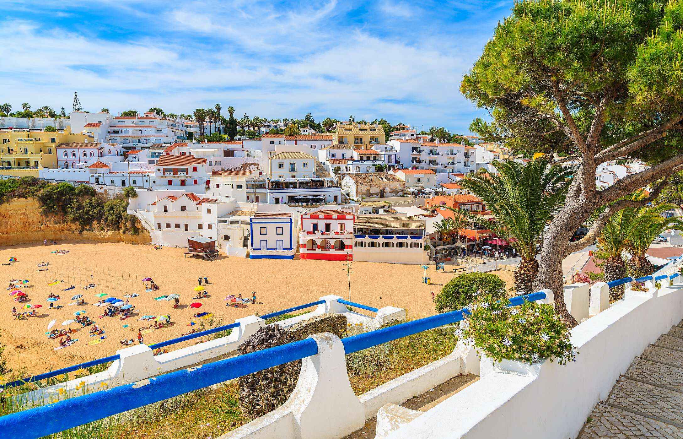 Panoramablick auf Praia do Carvoeiro, an der Algarve, mit Häusern, die auf den Klippen gebaut sind, und goldenem Sand