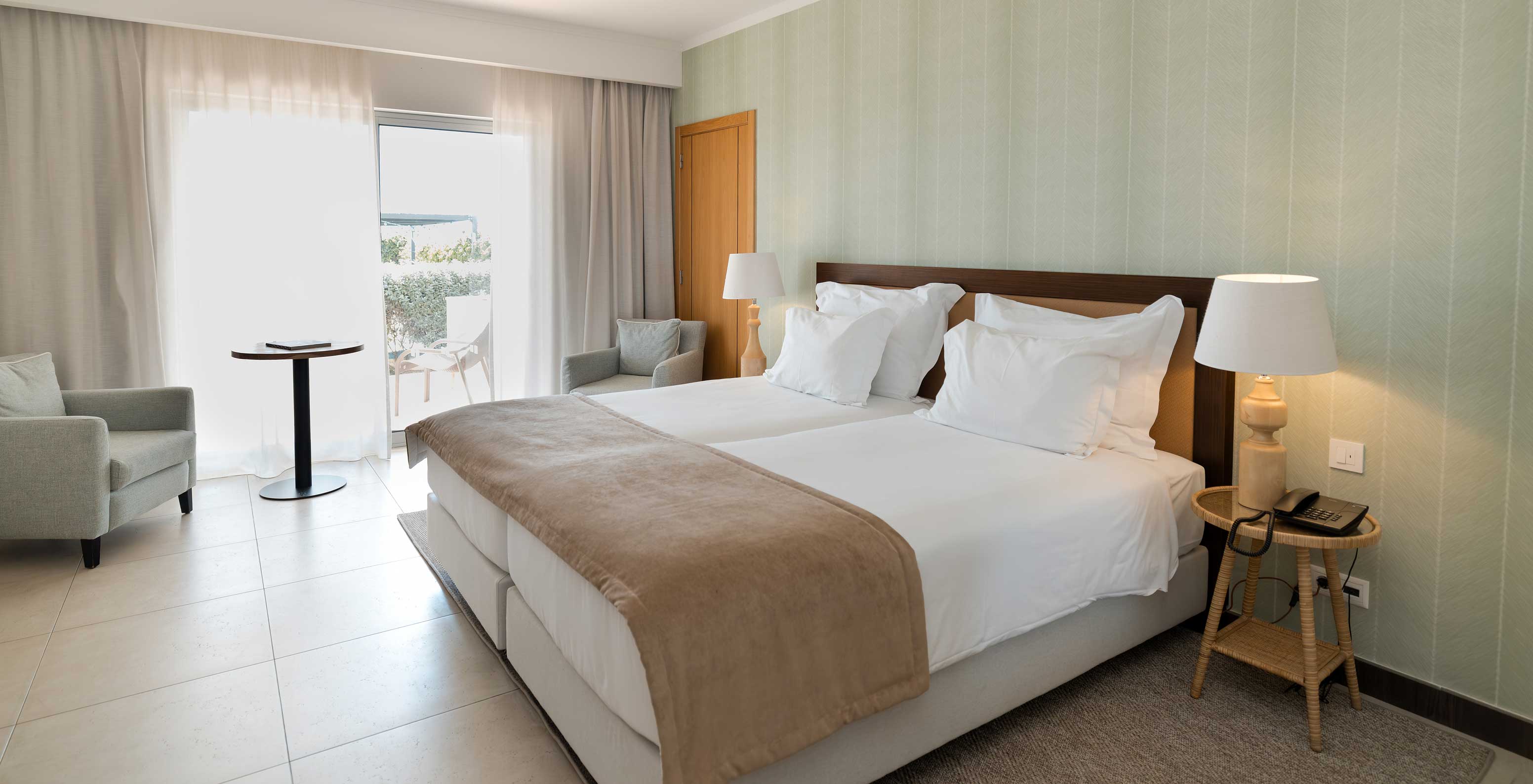 Studio Gartenblick im Pestana Alvor Beach Villas hat zwei Betten, grüne Tapete und Fenster mit Balkon