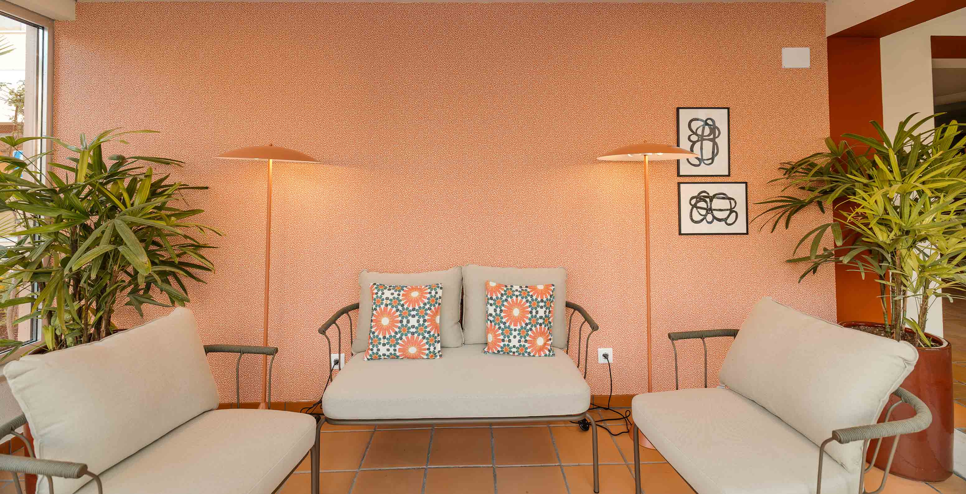 Lobby im Strandhotel mit Pool, orangefarbener Tapete, drei bequemen beigen Sofas und heller, einladender Deko