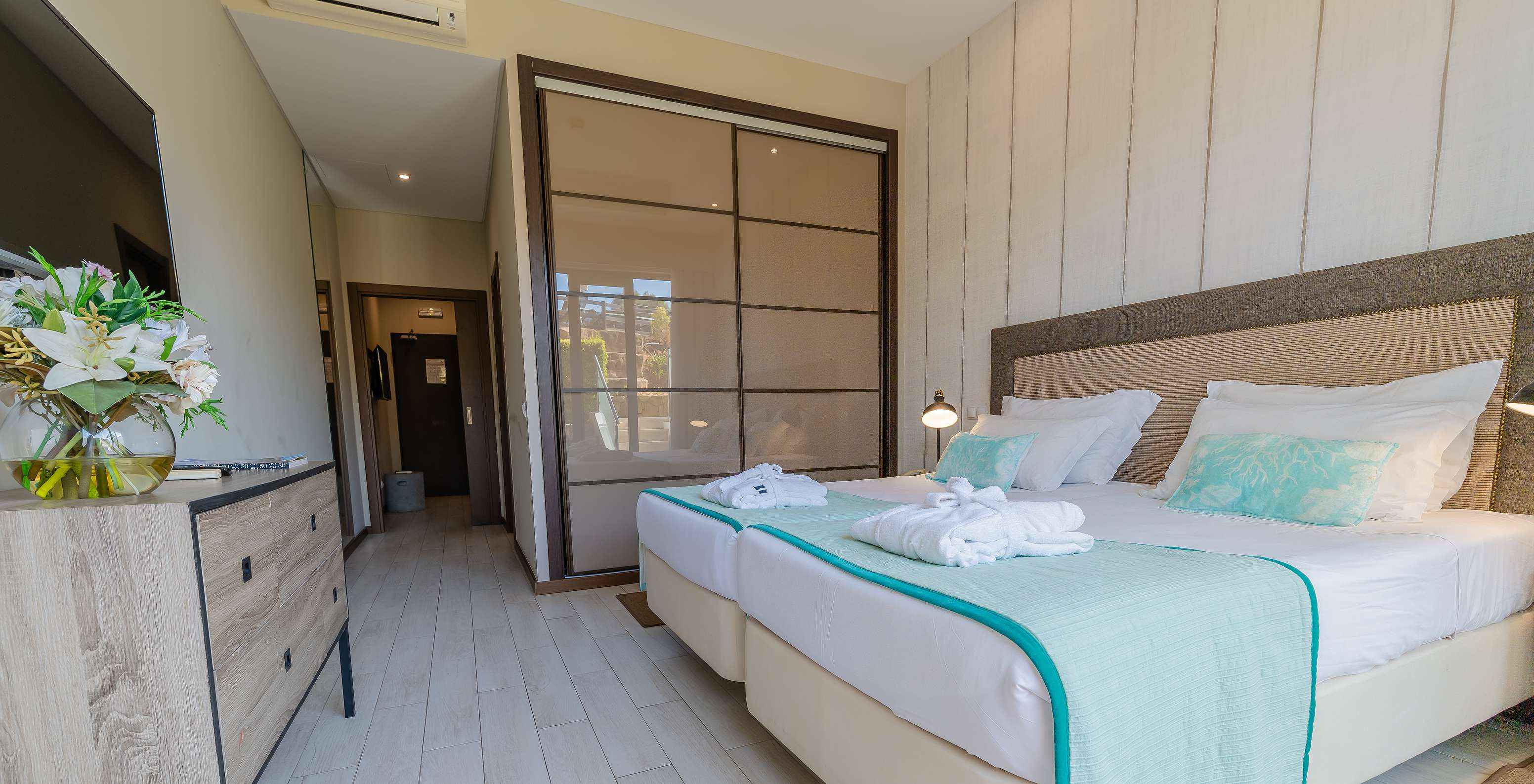 Die Garden Suite im Pestana Alvor Park hat zwei Betten mit einer Holzkommode, einem Fernseher und einem Schrank