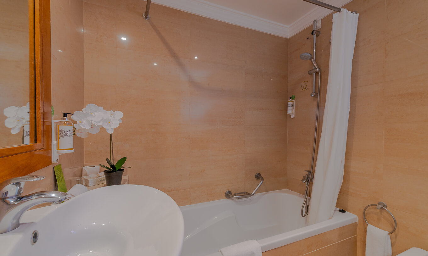 Das T0 - Studio im Pestana Alvor Park hat ein Badezimmer mit Badewanne mit Vorhang, Waschbecken und einer Blume