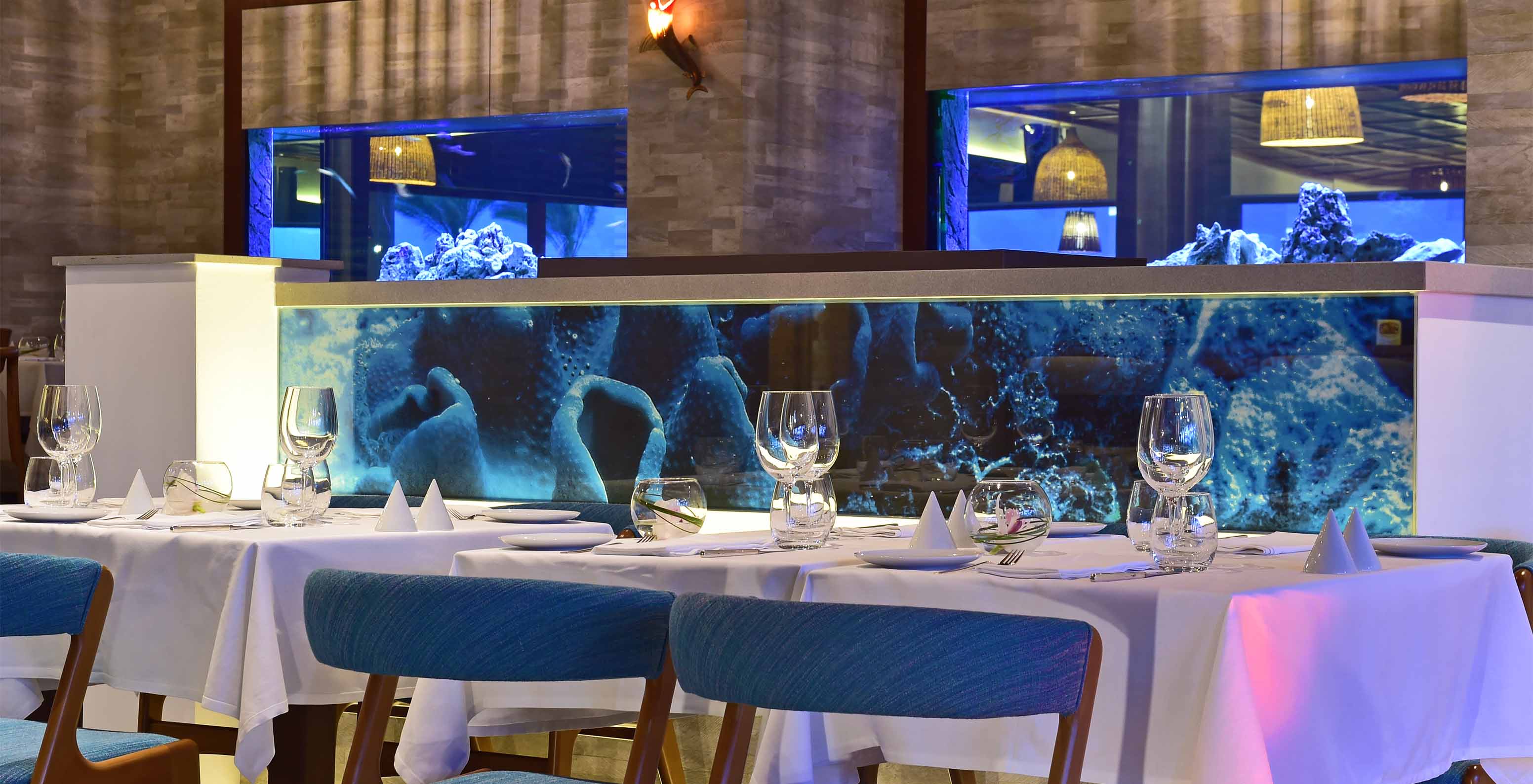 Das Restaurant Sul, im 5-Sterne-Hotel in der Algarve, hat Aquarien zwischen den Bereichen und gepolsterte Stühle