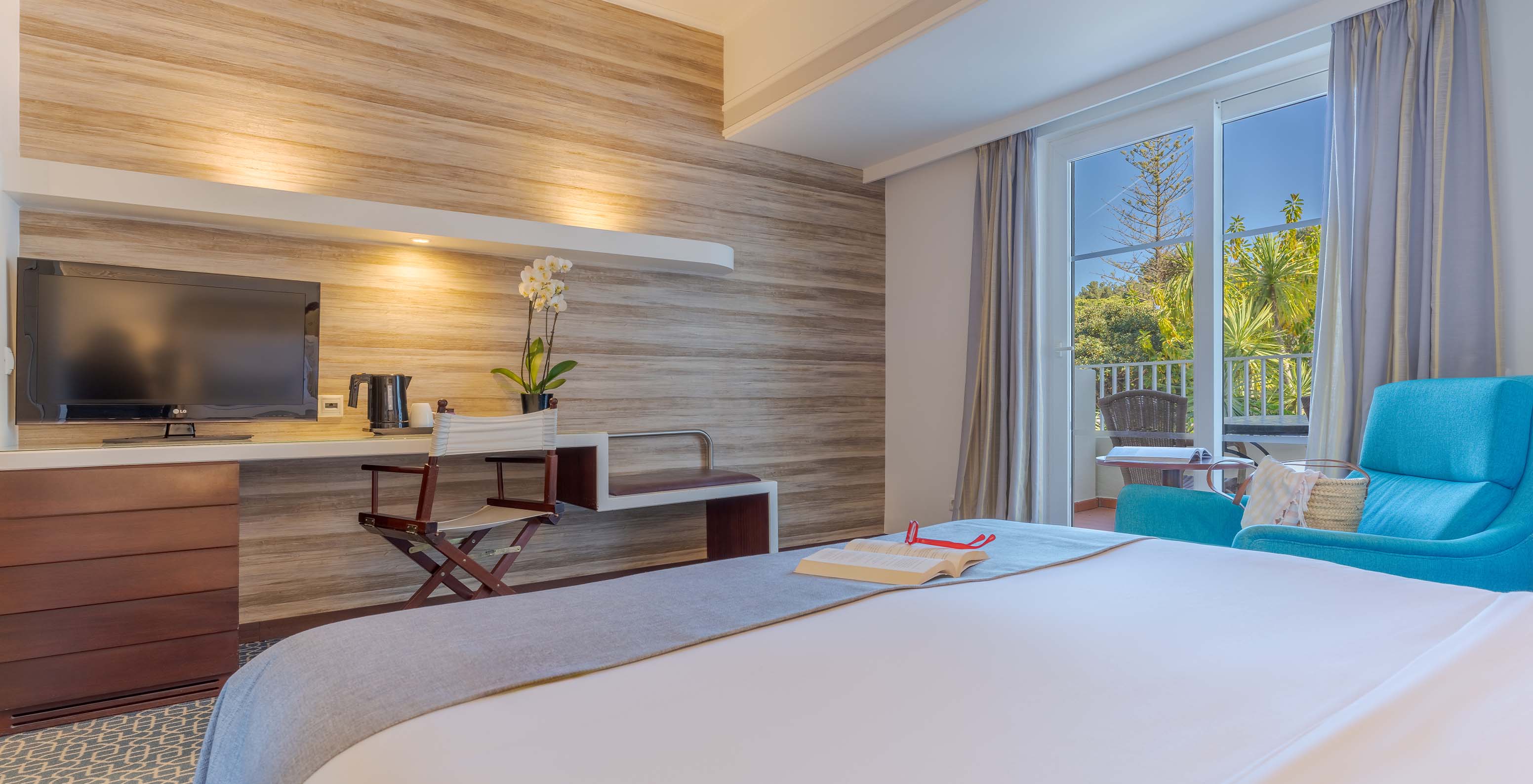 Das Deluxe im Pestana Alvor Praia hat ein Doppelbett, Fernseher am Schreibtisch, blauen Sessel und Fenster