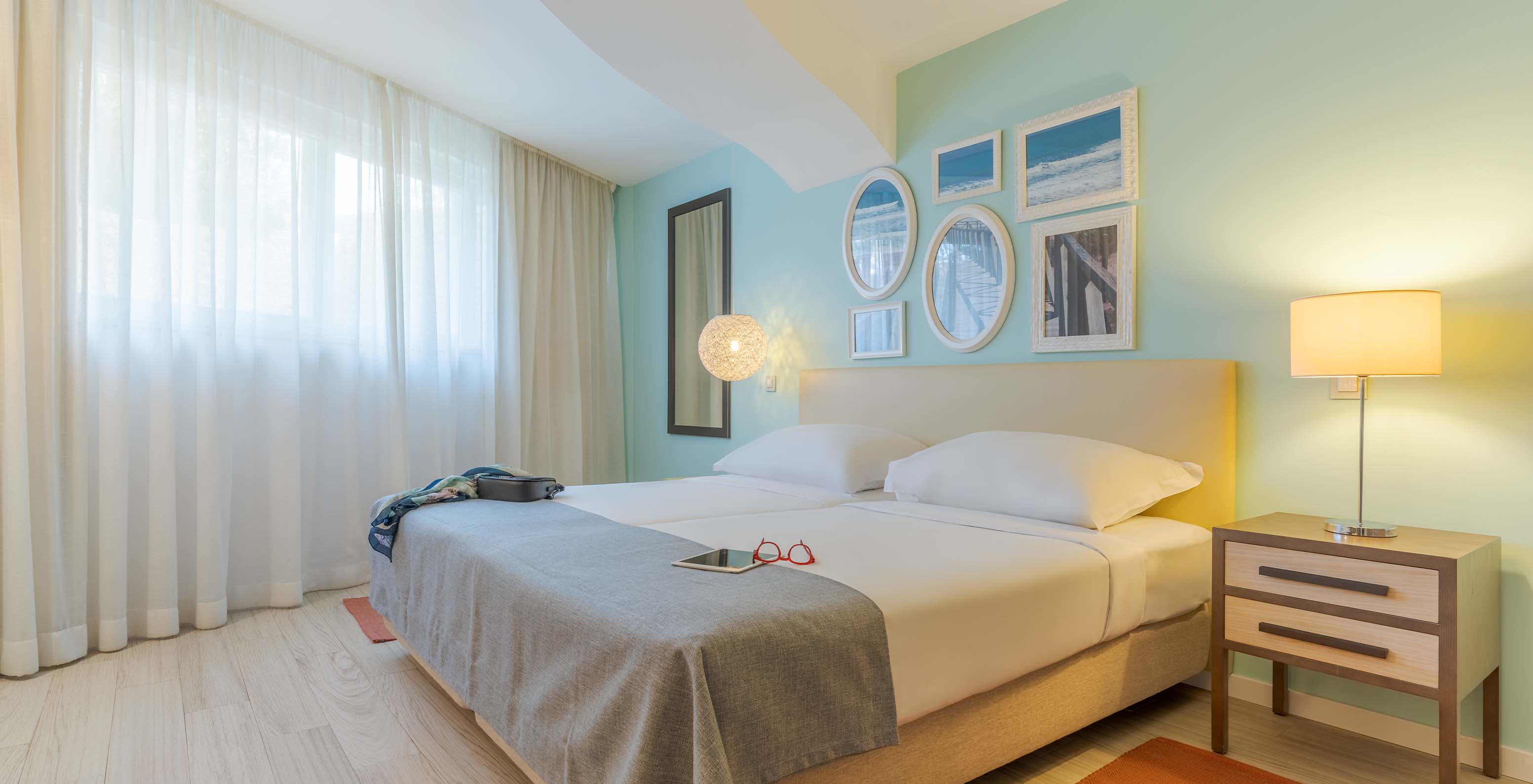 Die Suite T1 mit Gartenblick im Pestana Alvor Praia hat zwei Betten, Nachttisch mit Lampe, Teppich und Bilder