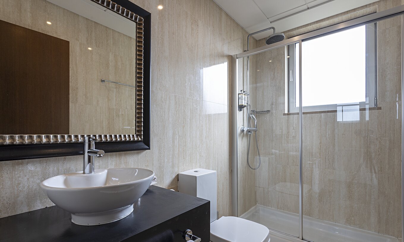 Die Cliff Suite T2 im Pestana Alvor Praia hat ein modernes Bad mit Fenster, Dusche, Waschbecken und Spiegel