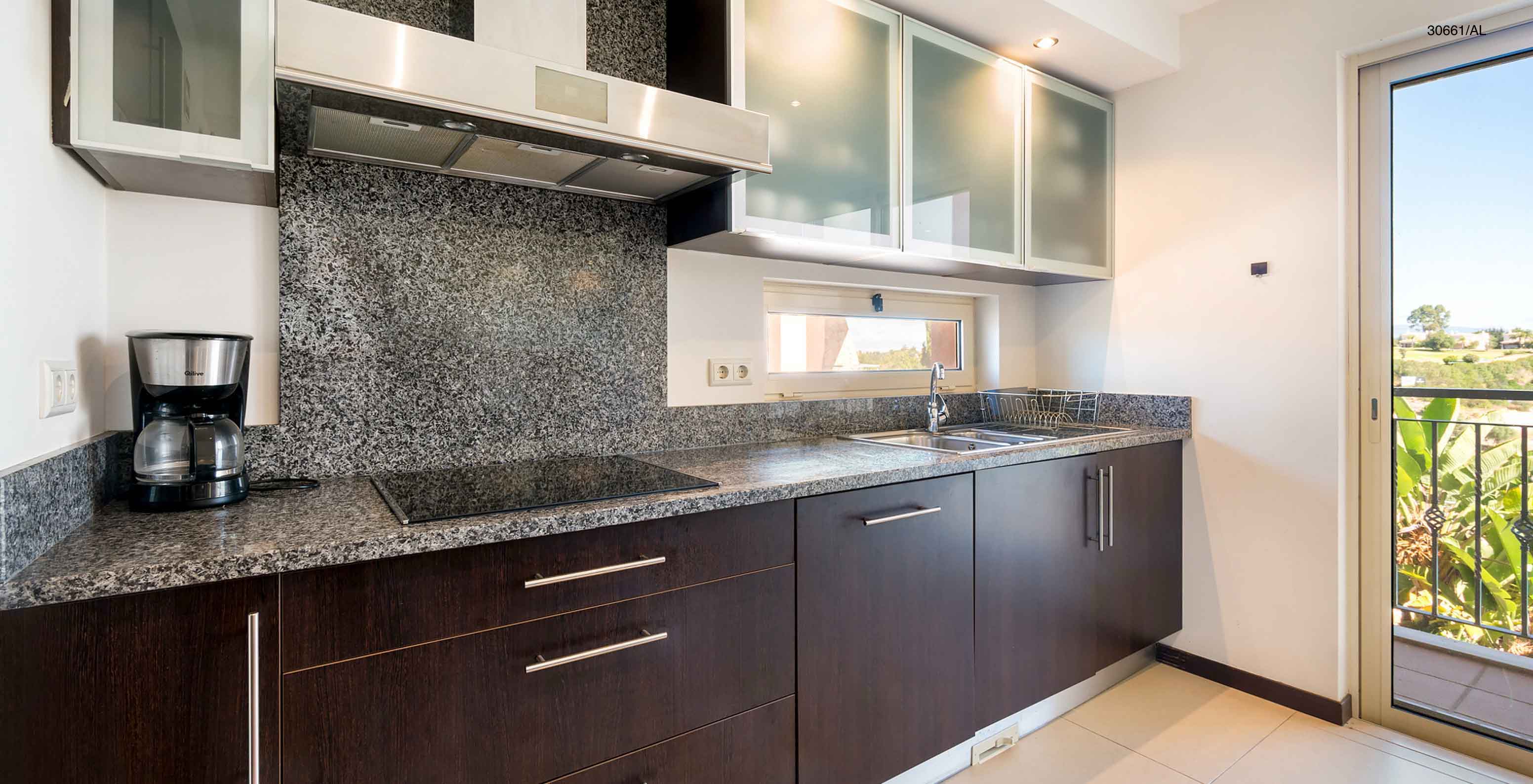 Die Wohnung Pestana Carvoeiro Golf T1 Superior hat eine Küche mit dunklen Holzschränken und Granitarbeitsplatte