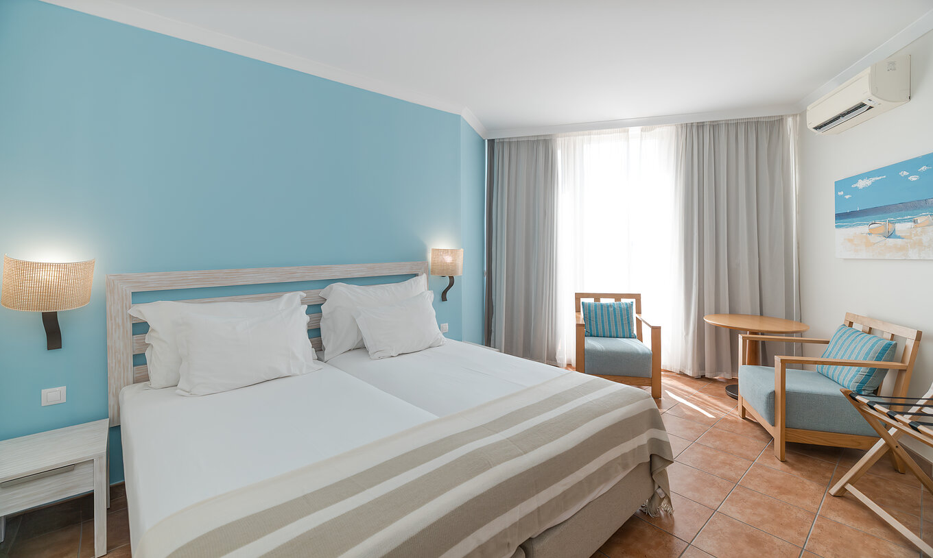 Das Deluxe Meerblick im Pestana Viking hat zwei Betten, Nachttisch, zwei Sessel und Klimaanlage