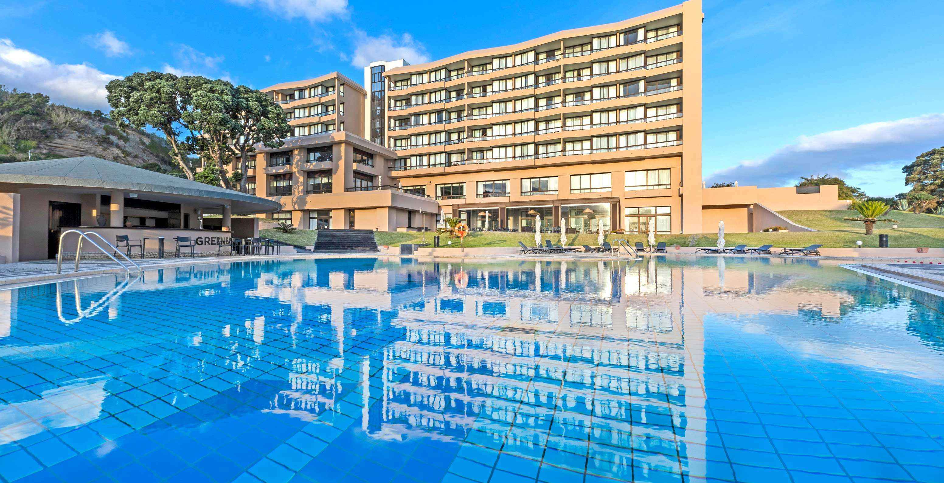 Außenschwimmbad im 4-Sterne-Hotel auf der Insel São Miguel mit Blick auf Liegen und das Hauptgebäude