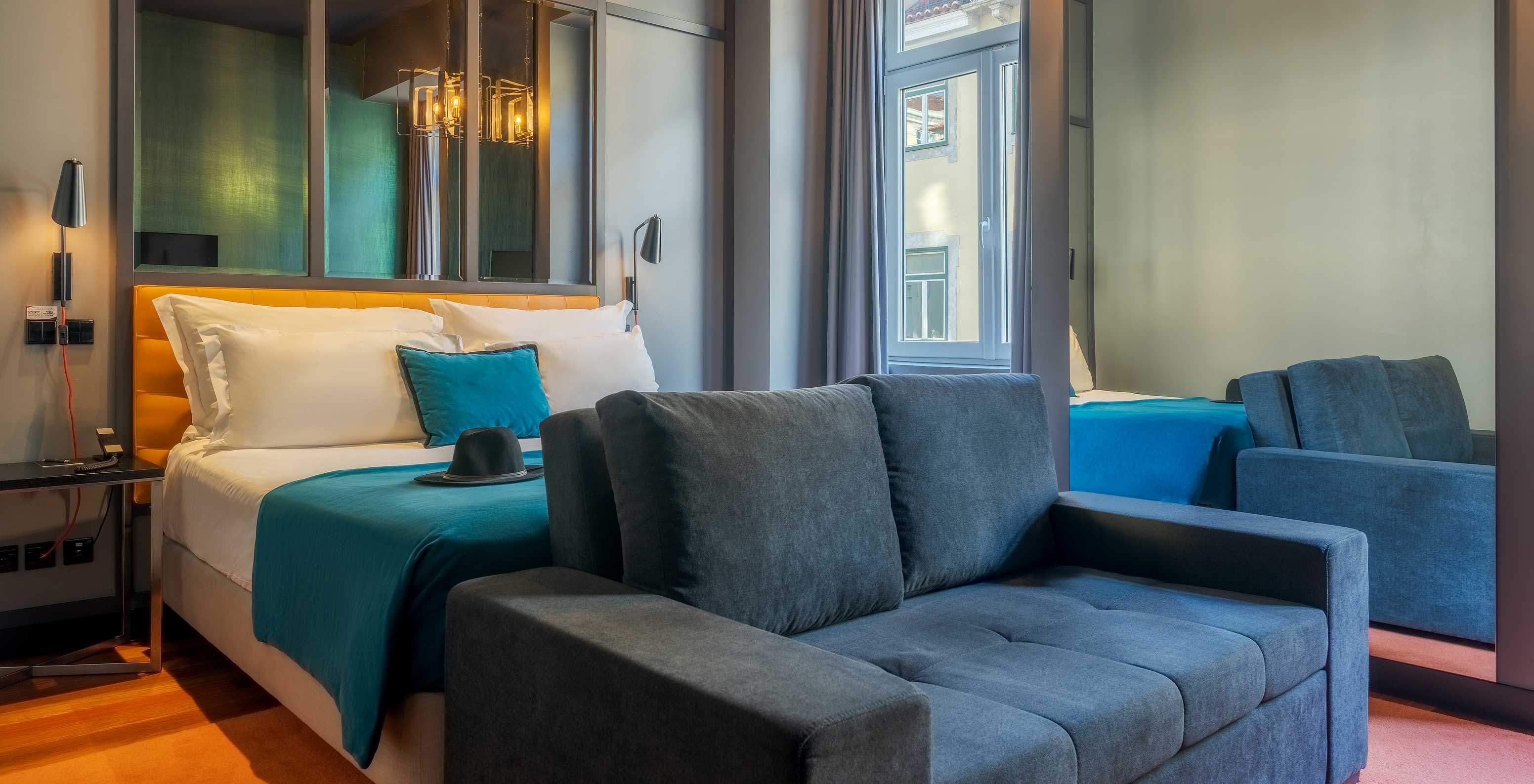 Das CR7 Familiar Hat-Trick hat ein Sofa ein Bett und einen Spiegel über dem Bett im Pestana CR7 Lisboa
