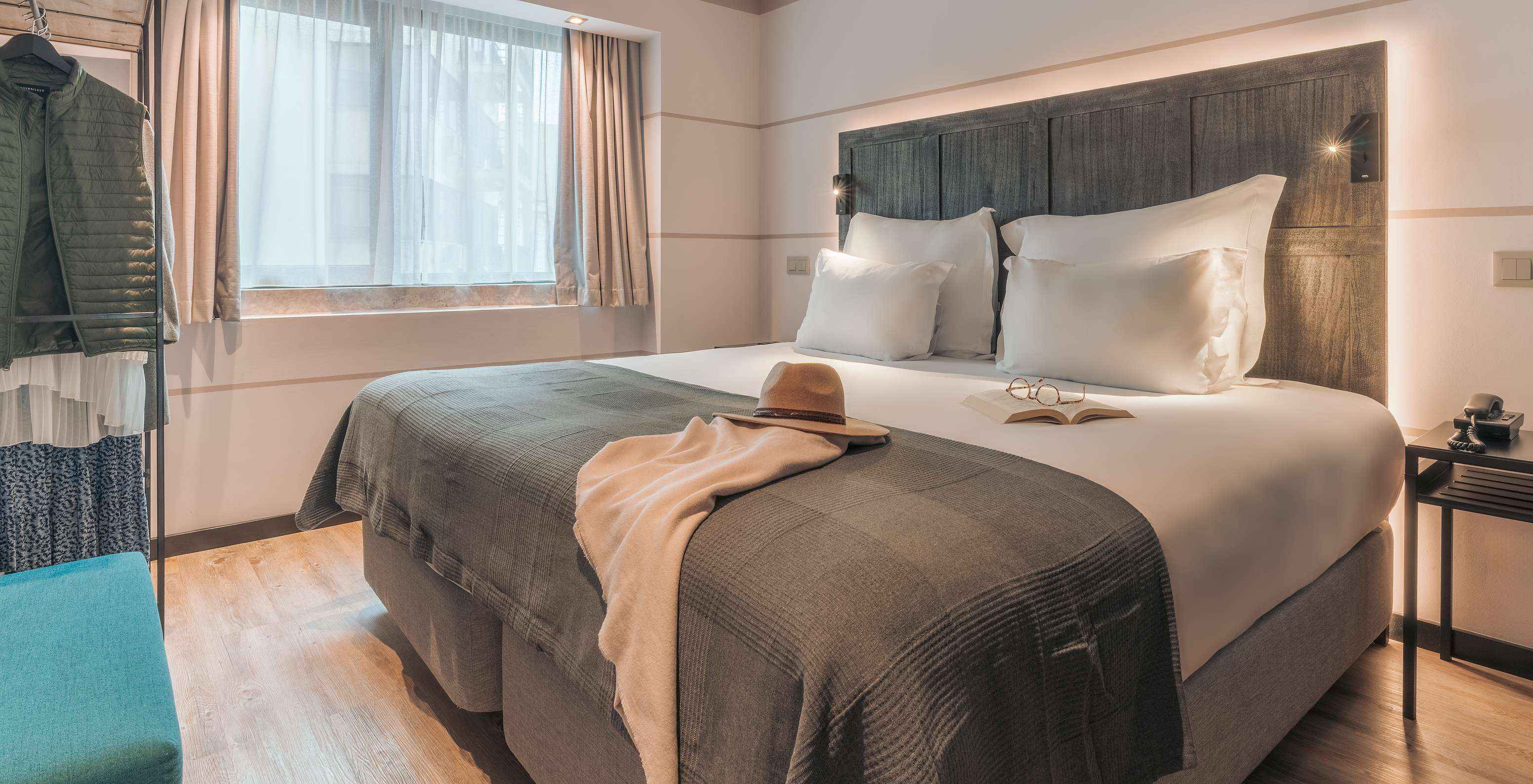 Die Junior Suite im Pestana Lisboa Vintage hat Doppelbett mit Decke, blauen Sofa, Nachttisch und Schrank