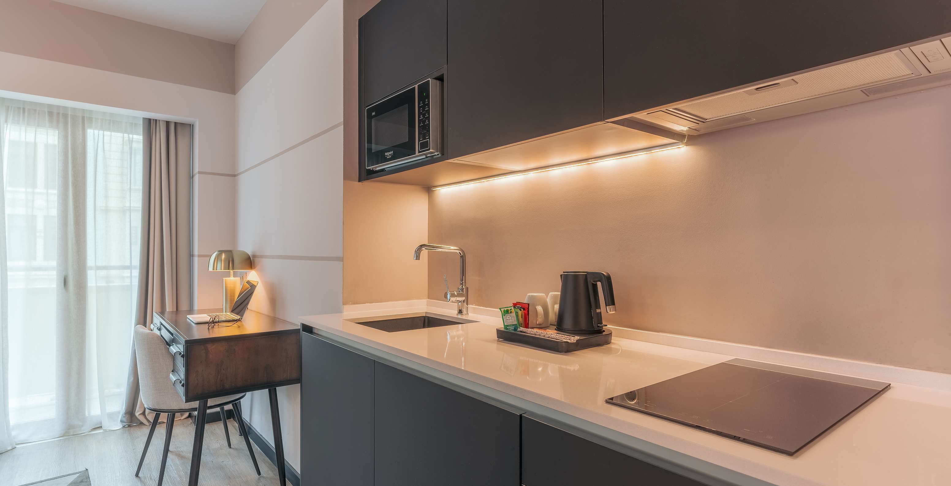 Die Junior Suite im Pestana Lisboa Vintage hat Küchenmöbel mit Herd, Mikrowelle und Schreibtisch mit Stuhl