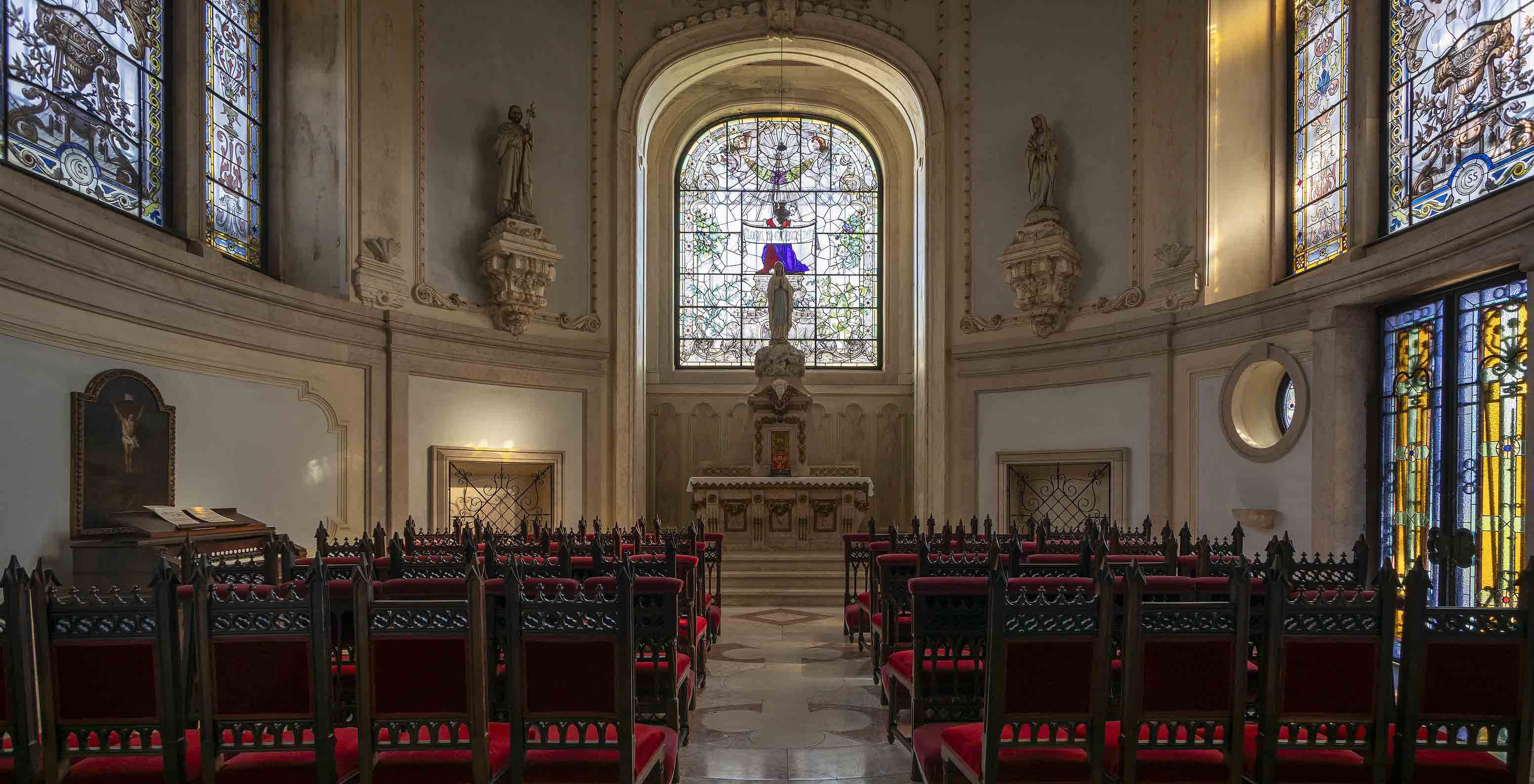 Das Pestana Palace Lisboa hat eine Kapelle mit einem kleinen Altar, mehreren bunten Glasfenstern und dunklen Holzstühlen