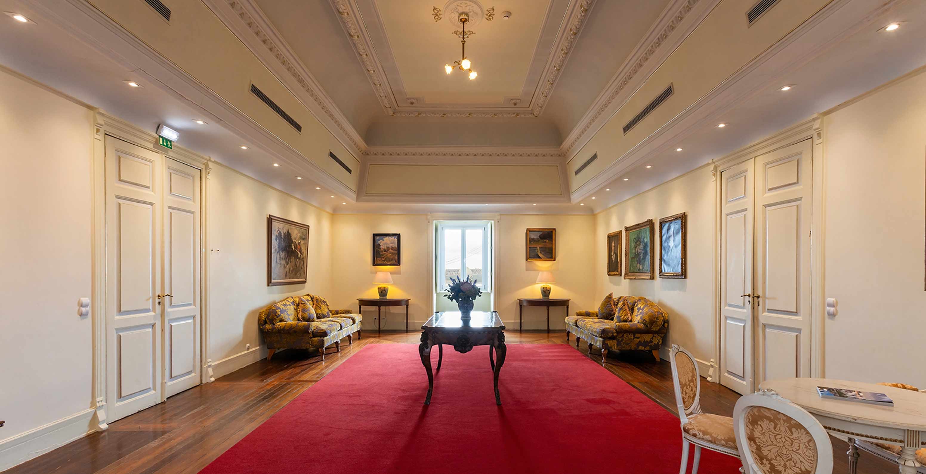 Das Pestana Palace Lisboa hat ein Foyer mit großem roten Teppich, zwei Sofas und einem Fenster in der Ecke	