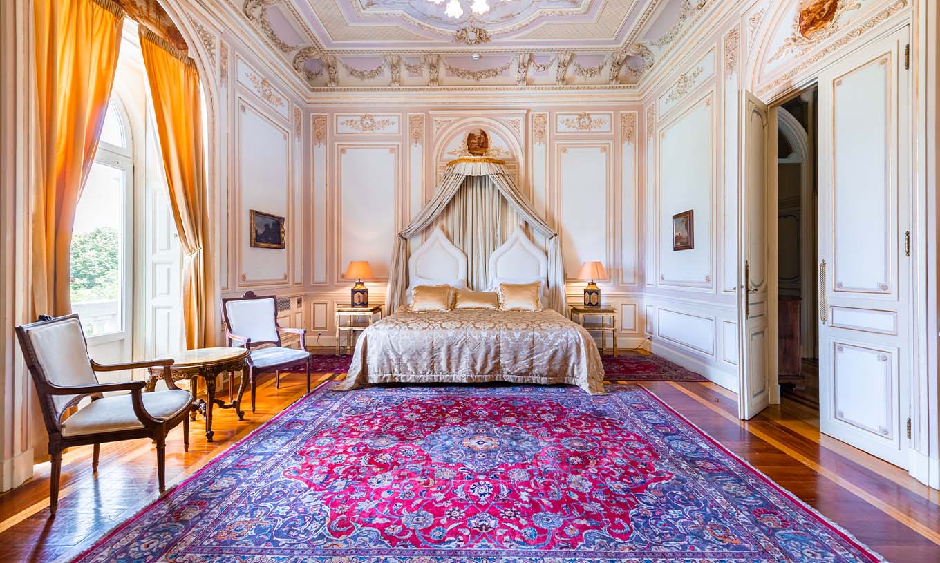 Die D. Carlos Suite im Pestana Palace Lisboa hat ein luxuriöses Zimmer mit Doppelbett und verzierten Decken