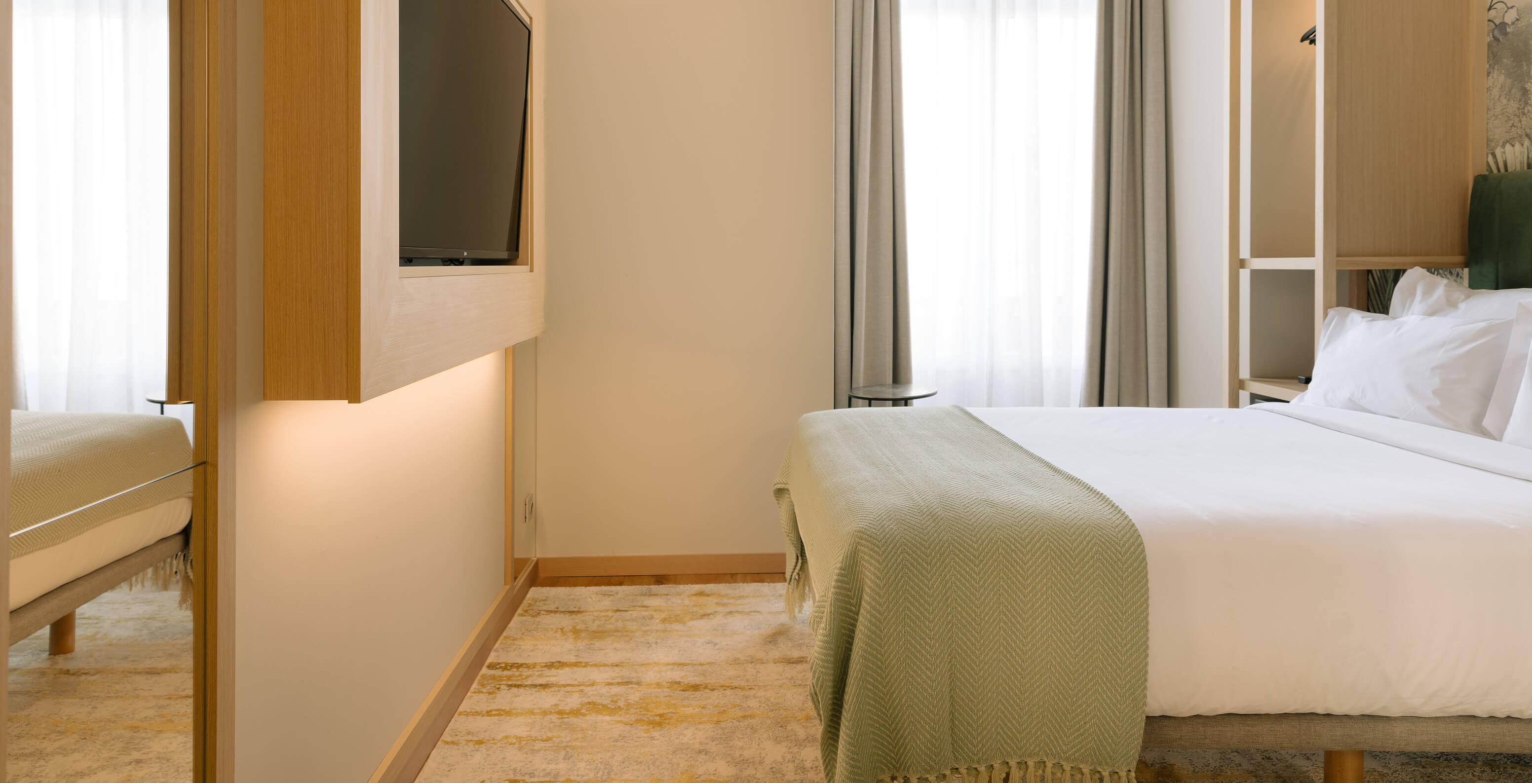 Das Cozy Zimmer im Pestana Rua Augusta Lisboa hat ein Doppelbett, Fernseher und ein Fenster mit Vorhängen