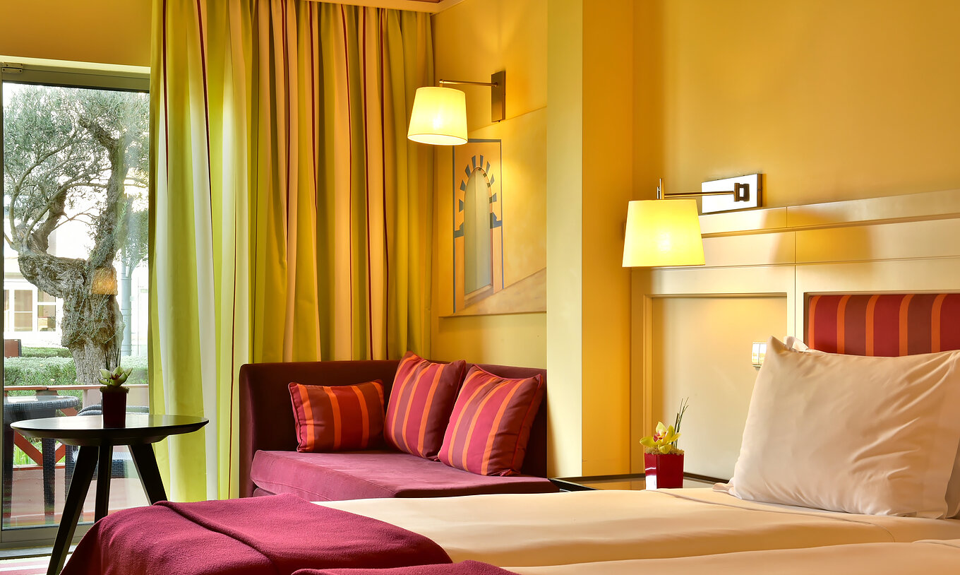 Das Superior Doppelzimmer mit Poolblick hat zwei Betten und einen Sofa mit Tisch