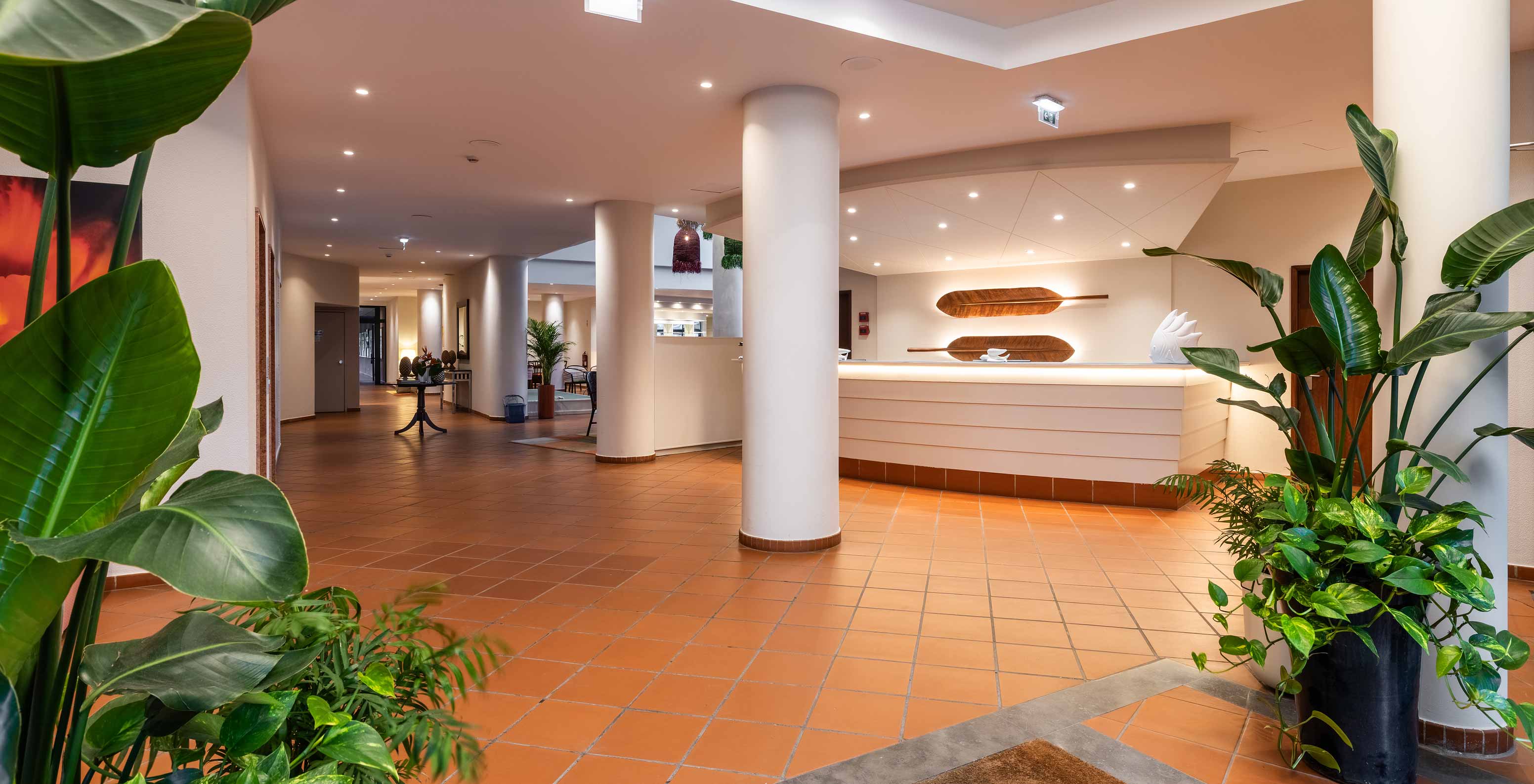 Pestana Ocean Bay All Inclusive, ein All-Inclusive-Hotel mit einer weißen Rezeption, die mit Pflanzen dekoriert ist