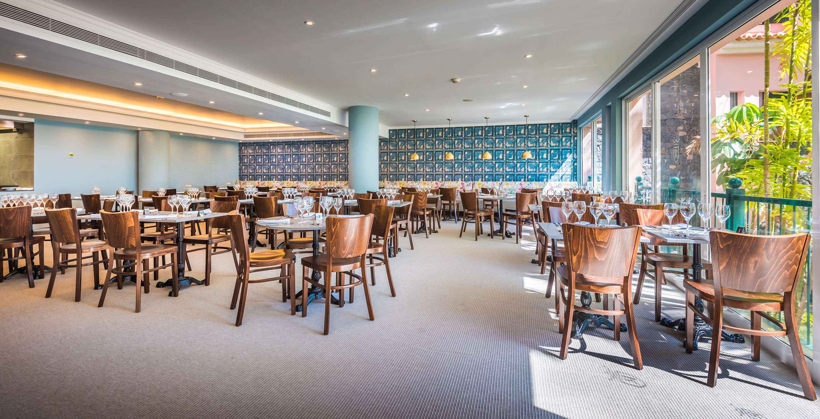 Das Restaurant Campo de Fiori, im 5-Sterne-Hotel mit All-Inclusive in Funchal, hat Tische, Stühle und eine bunte Wand