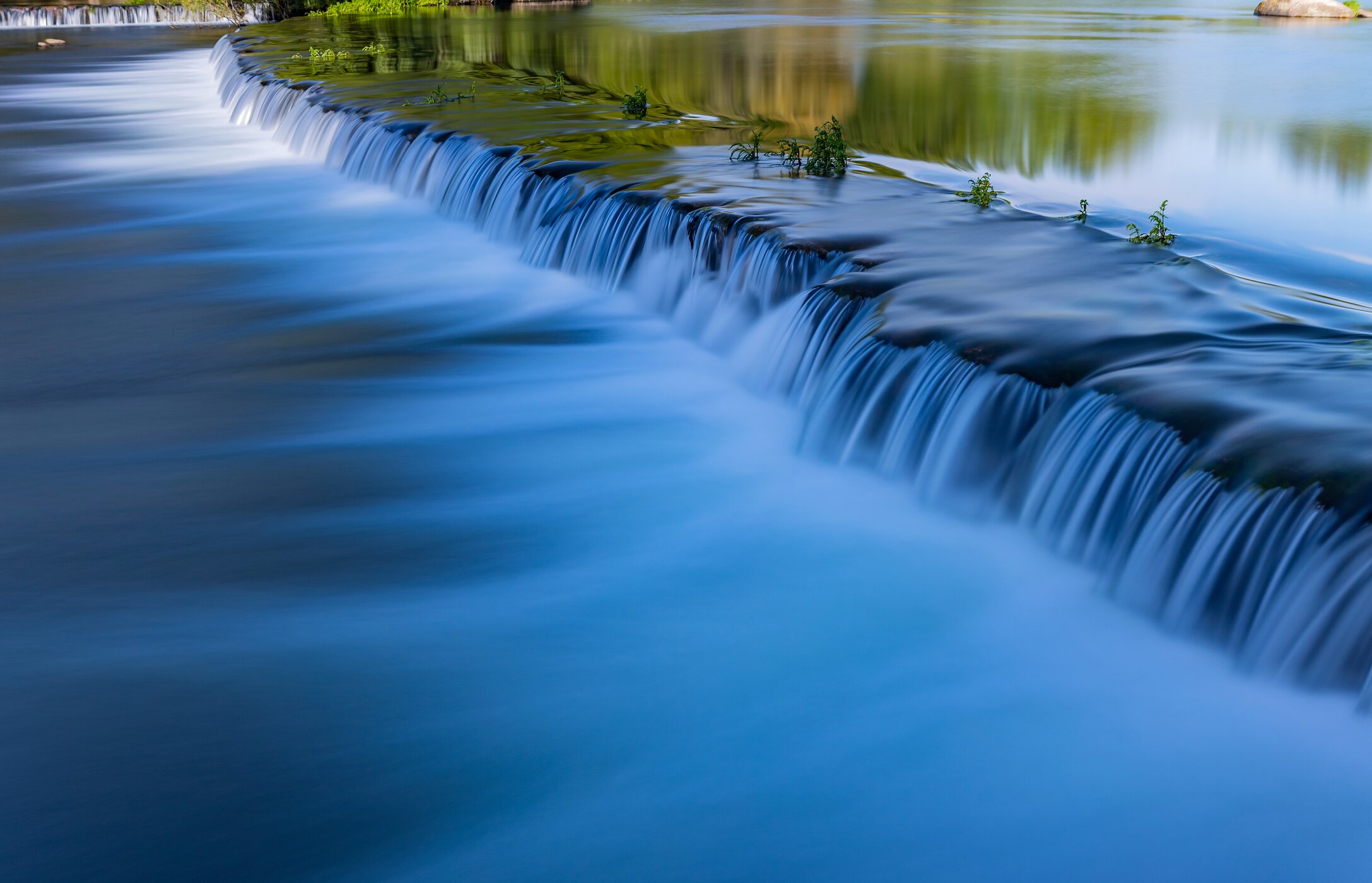 Panoramablick auf den Strand von Adaufe, mit kristallklarem Wasser, umgeben von Felsen und Vegetation