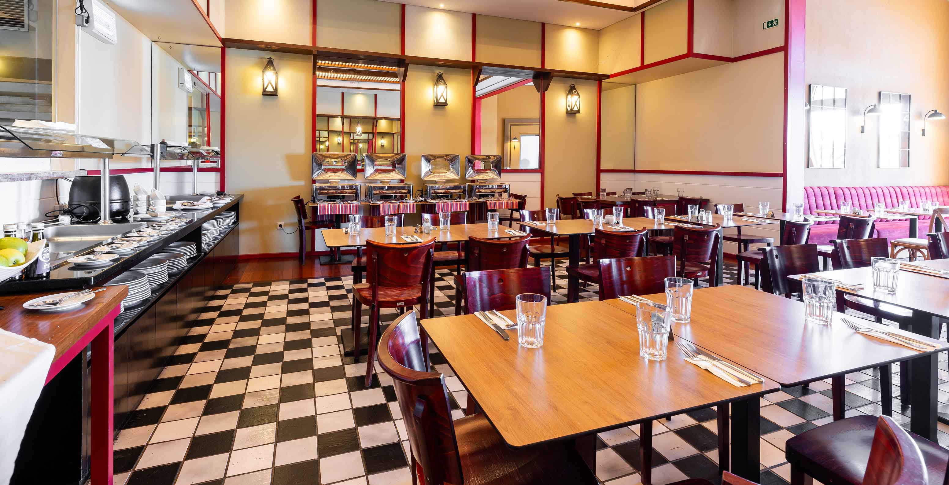 Das Restaurant Luigi im 5-Sterne-Resort auf Porto Santo hat einen Boden mit schwarzen und weißen Fliesen und dunkle Stühle.