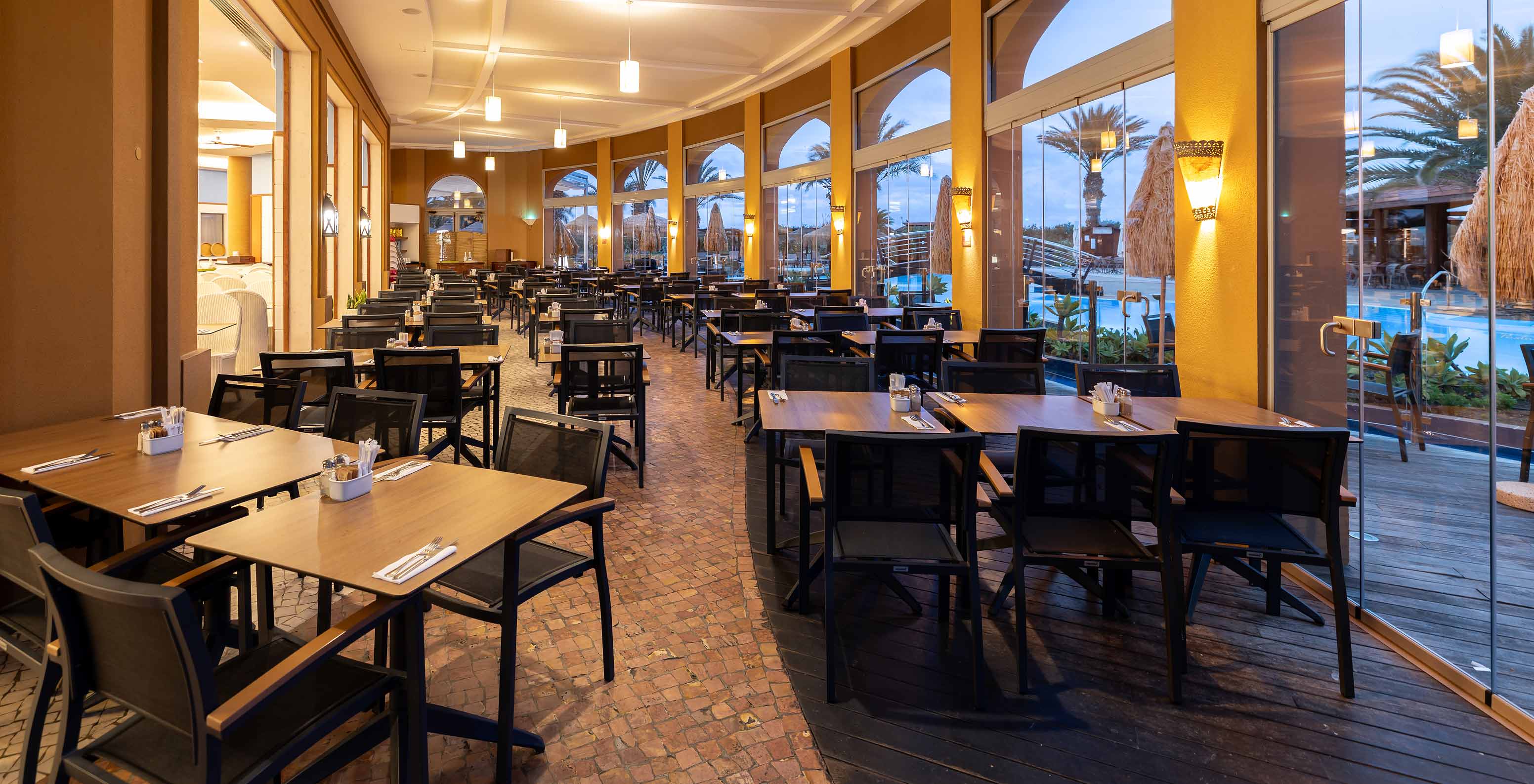 Das Restaurant Marés im 5-Sterne-Resort auf Porto Santo hat einen Außenbereich mit quadratischen Tischen und Stühlen.