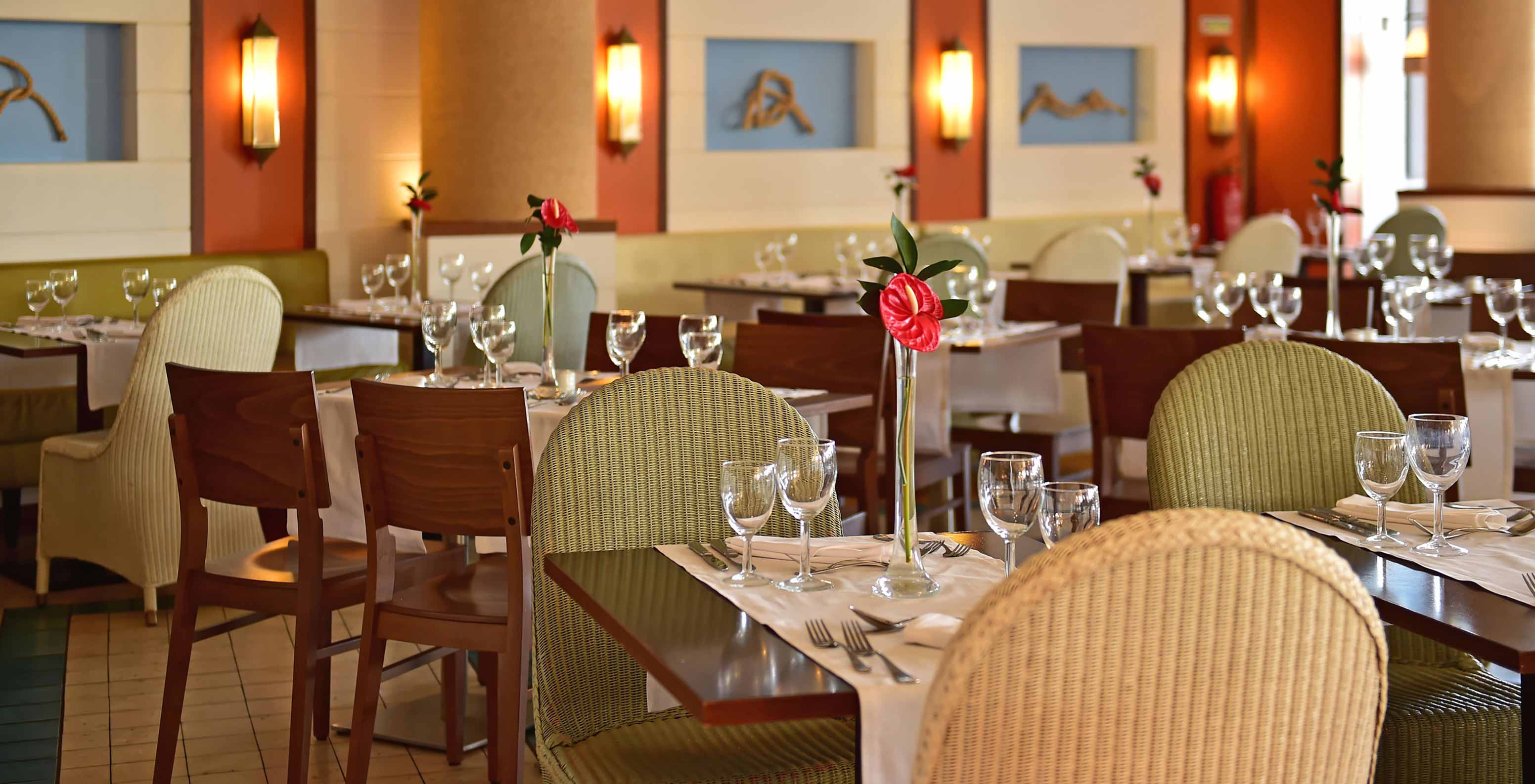 Restaurant Marés, 5-Sterne-Resort in Porto Santo hat einen Bereich mit grünen Stühlen und Holztischen