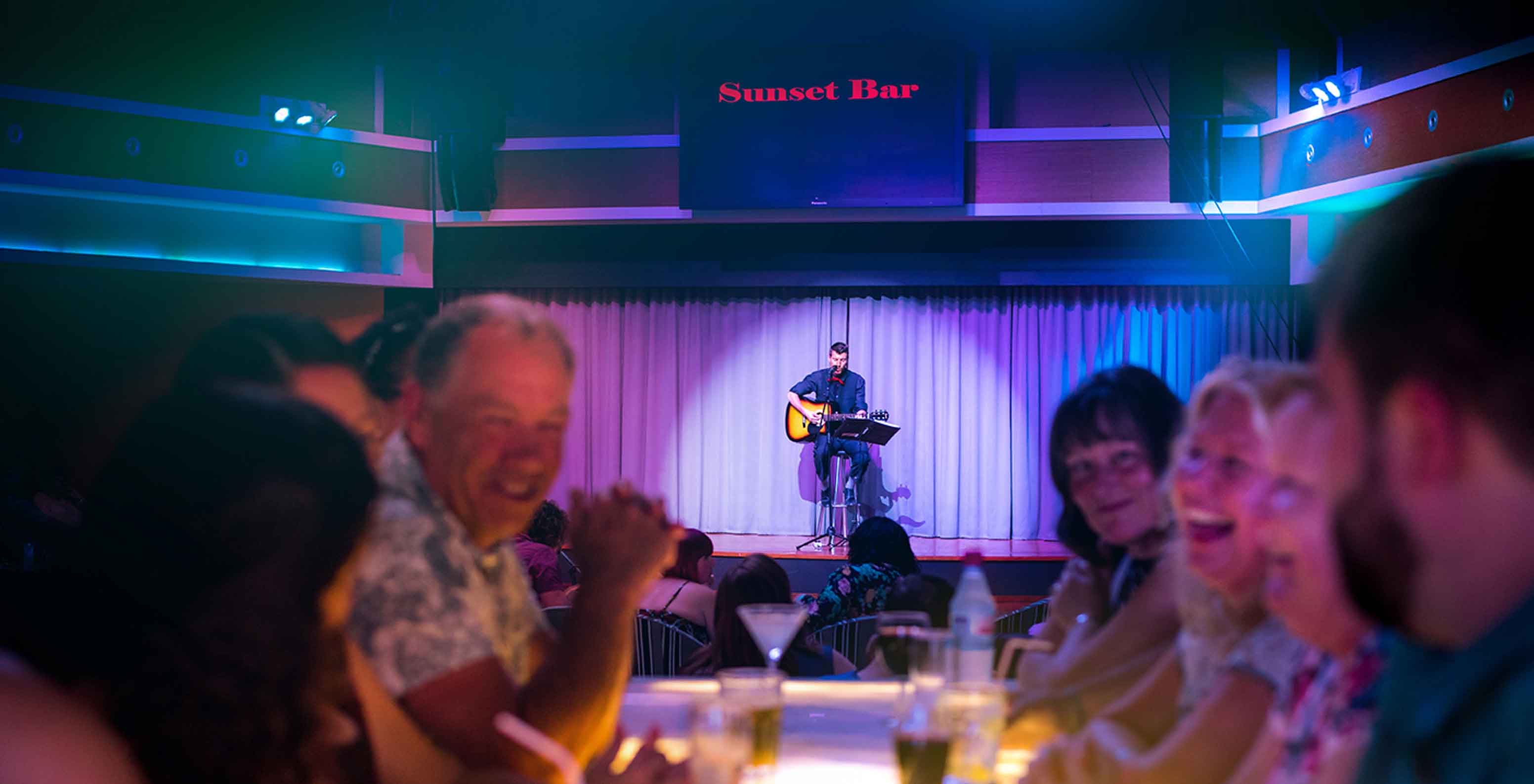 Sunset Bar, 5-Sterne-Resort in Porto Santo hat eine Bühne mit einem singenden Mann und zuschauenden Leuten