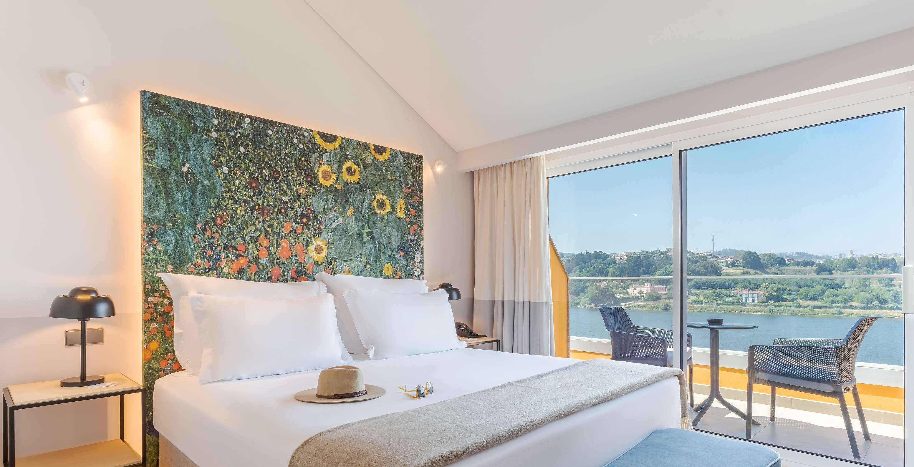 Die Junior Suite im Pestana Douro Riverside hat ein Doppelbett, Nachttisch mit Lampe und Balkon