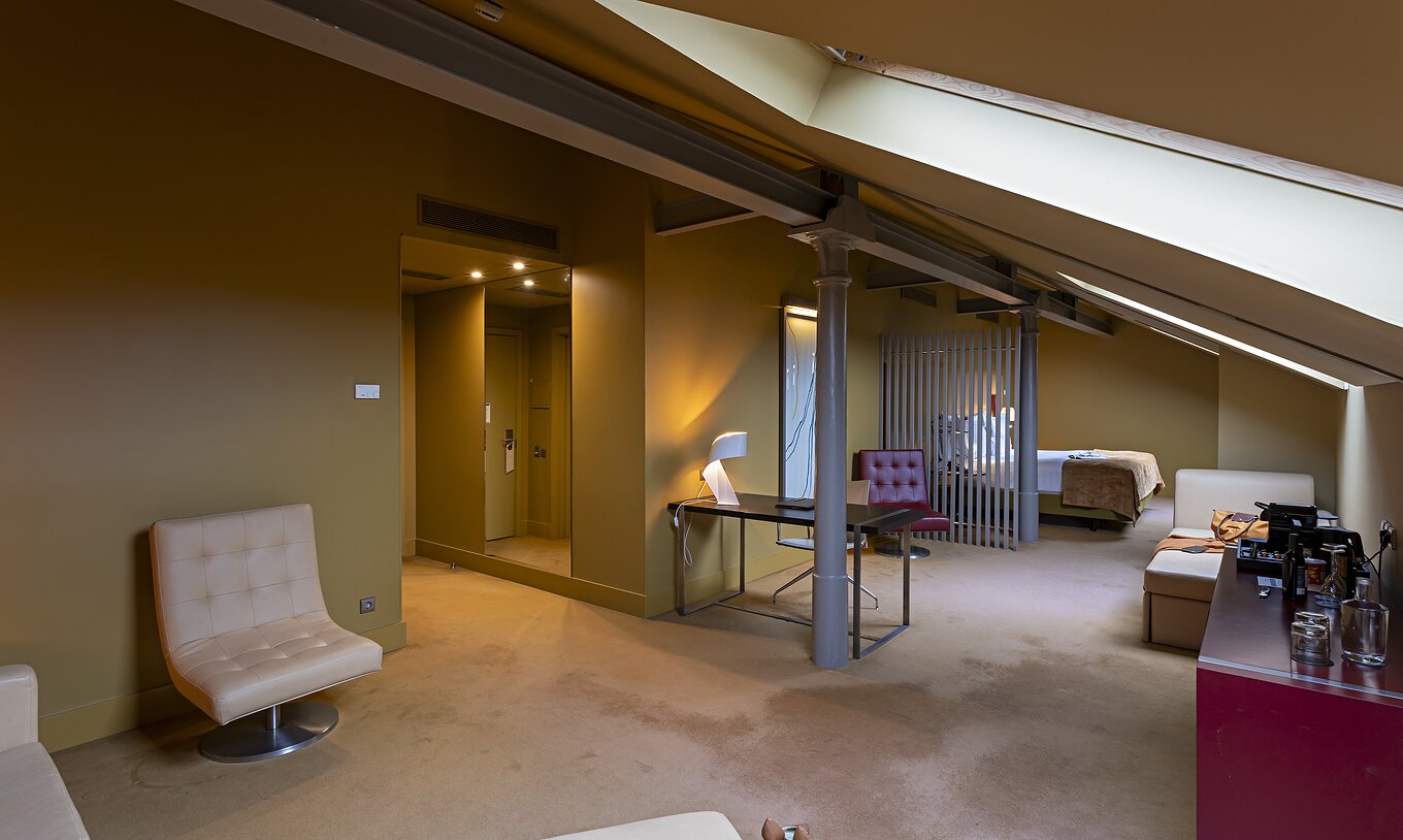 Das Loft Attic im Pestana Palácio do Freixo hat ein beigefarbenes Ledersofa, Schreibtisch und roten Schrank