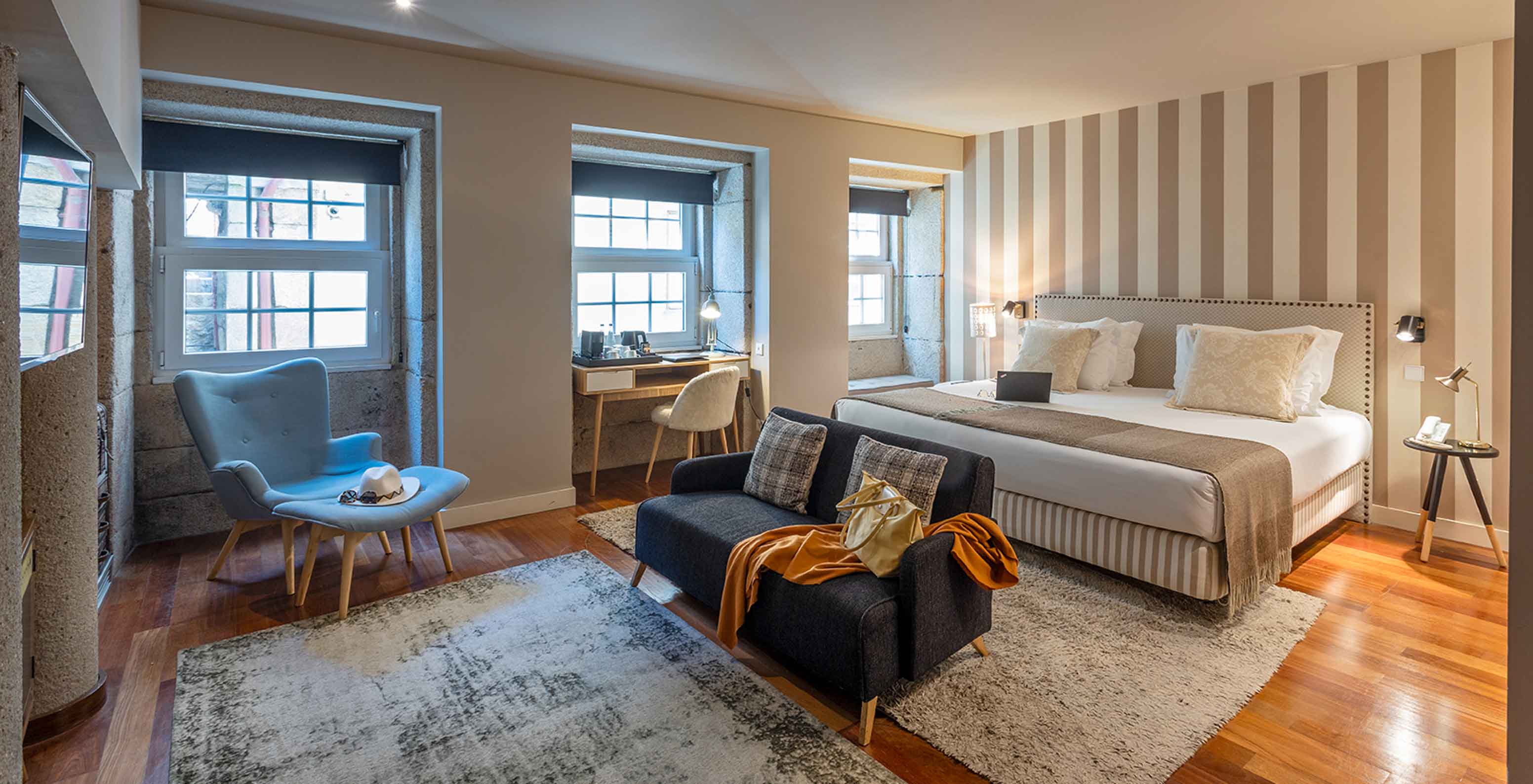 Die Heritage Suite des Pestana Vintage Porto verfügt über ein Doppelbett, zwei Sofas auf Teppichen und mehrere Fenster