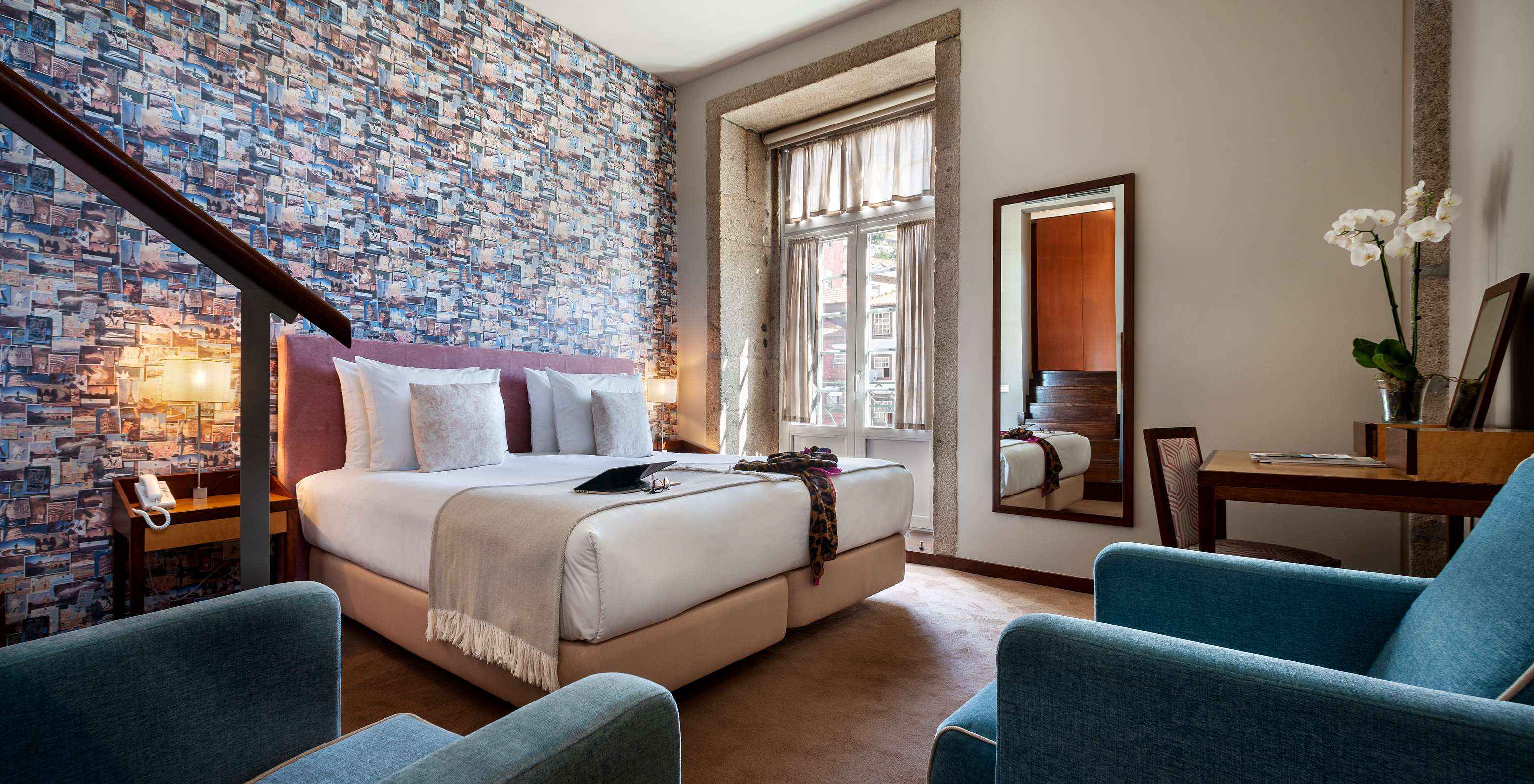 Plaza Pestana Vintage Porto hat ein Doppelbett, eine Tapete mit Reisefotos und einen Sessel