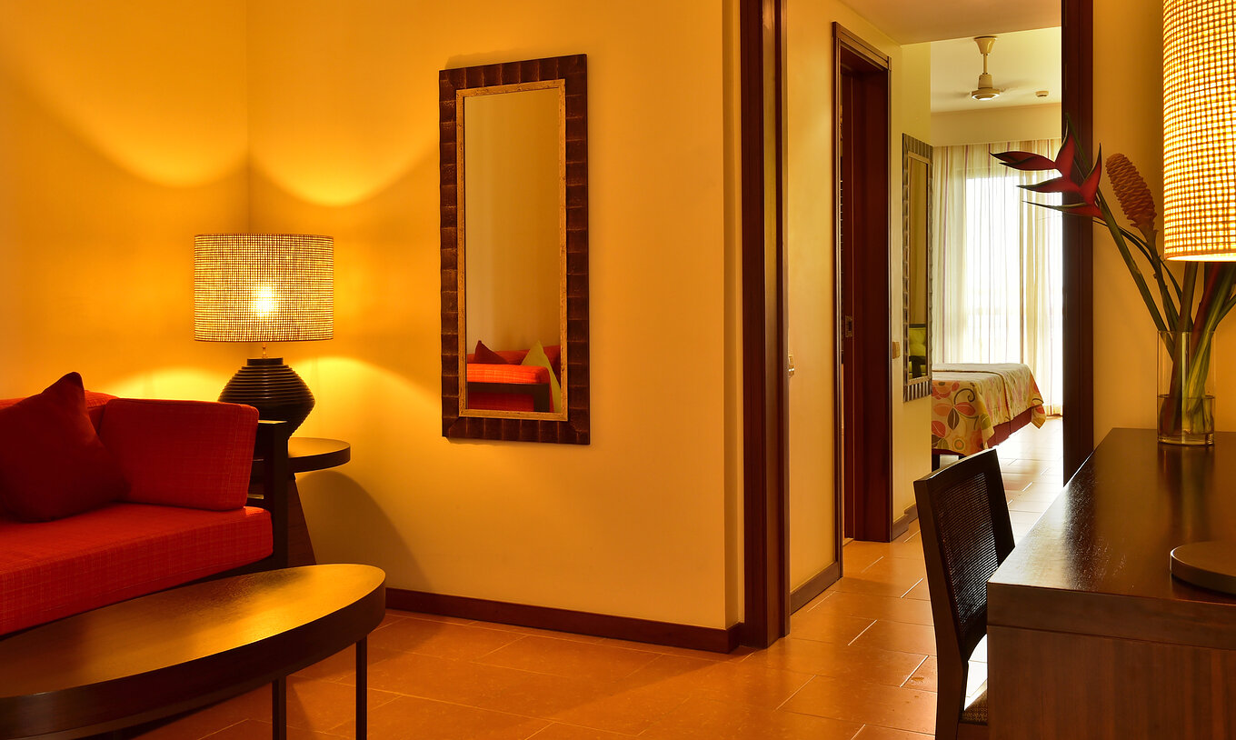 Die Junior Suite im Pestana São Tomé hat ein Wohnzimmer mit rotem Sofa und einen Schreibtisch