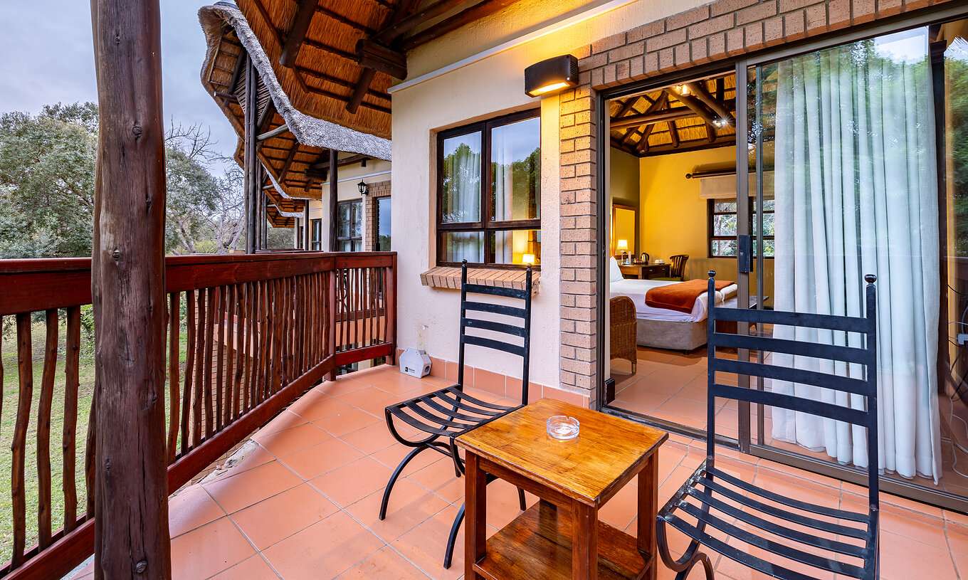 Das Klassische Zimmer im Pestana Kruger Lodge hat Balkon mit Holzelementen, zwei Stühle und Tisch