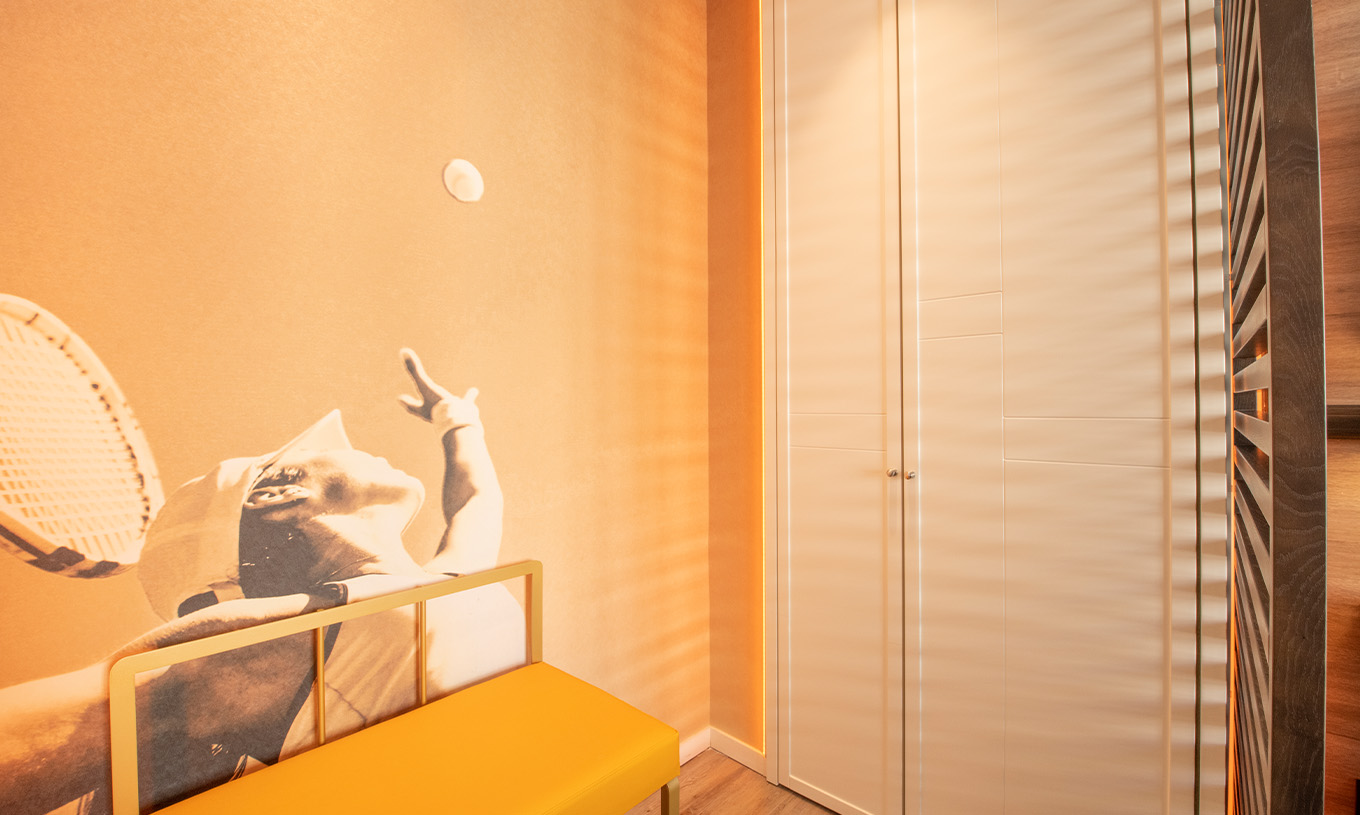 Das Legend Zimmer im Pestana CR7 Gran Vía Madrid hat einen Schrank, eine Bank und ein Foto eines Tennisspielers als Tapete