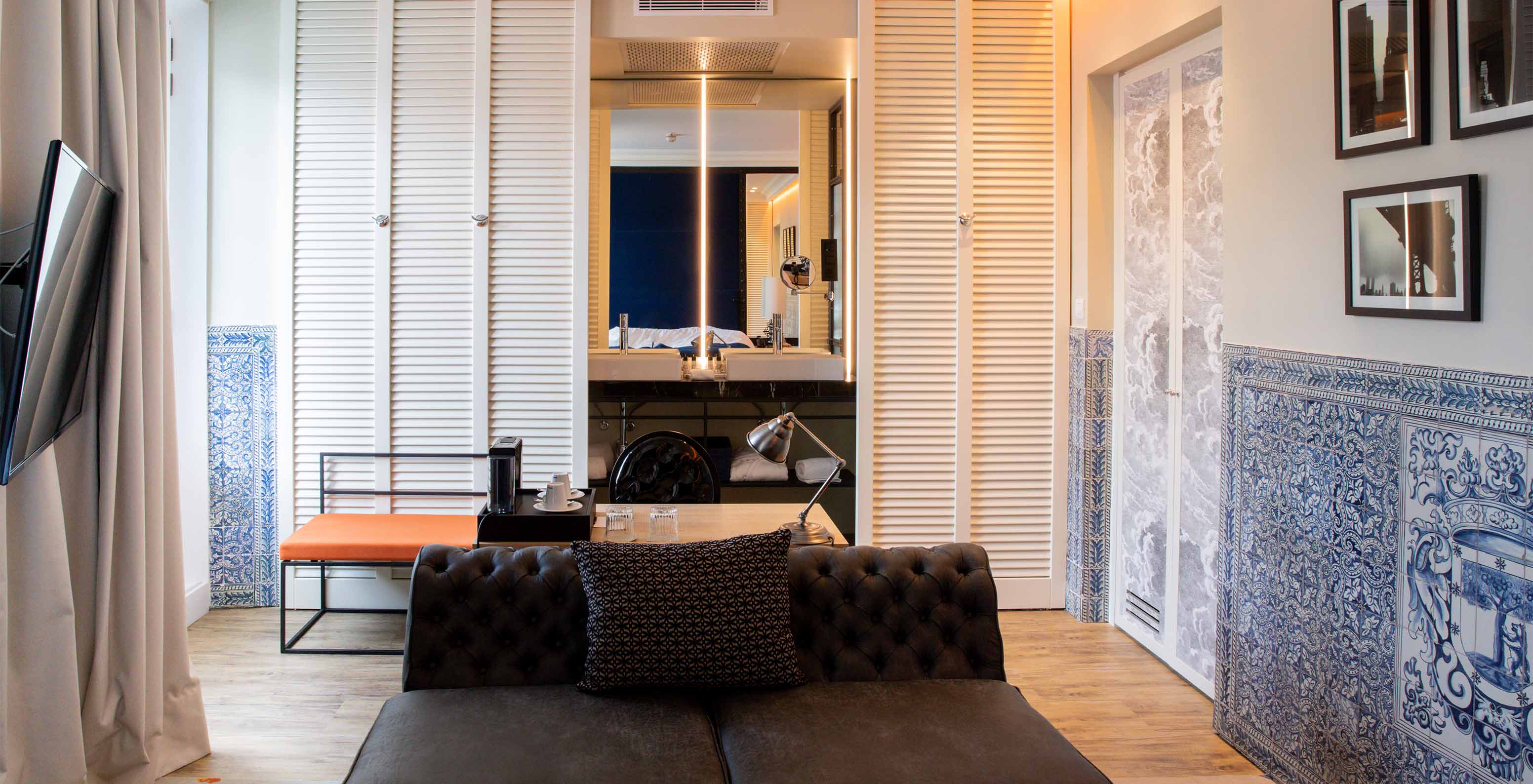 Das Deluxe Plaza Mayor im  Klassisches Zimmer - Kaffee - Pestana Collection Plaza Mayor hat ein Zimmer mit Sofa, Fernseher und blauen und weißen Fliesen