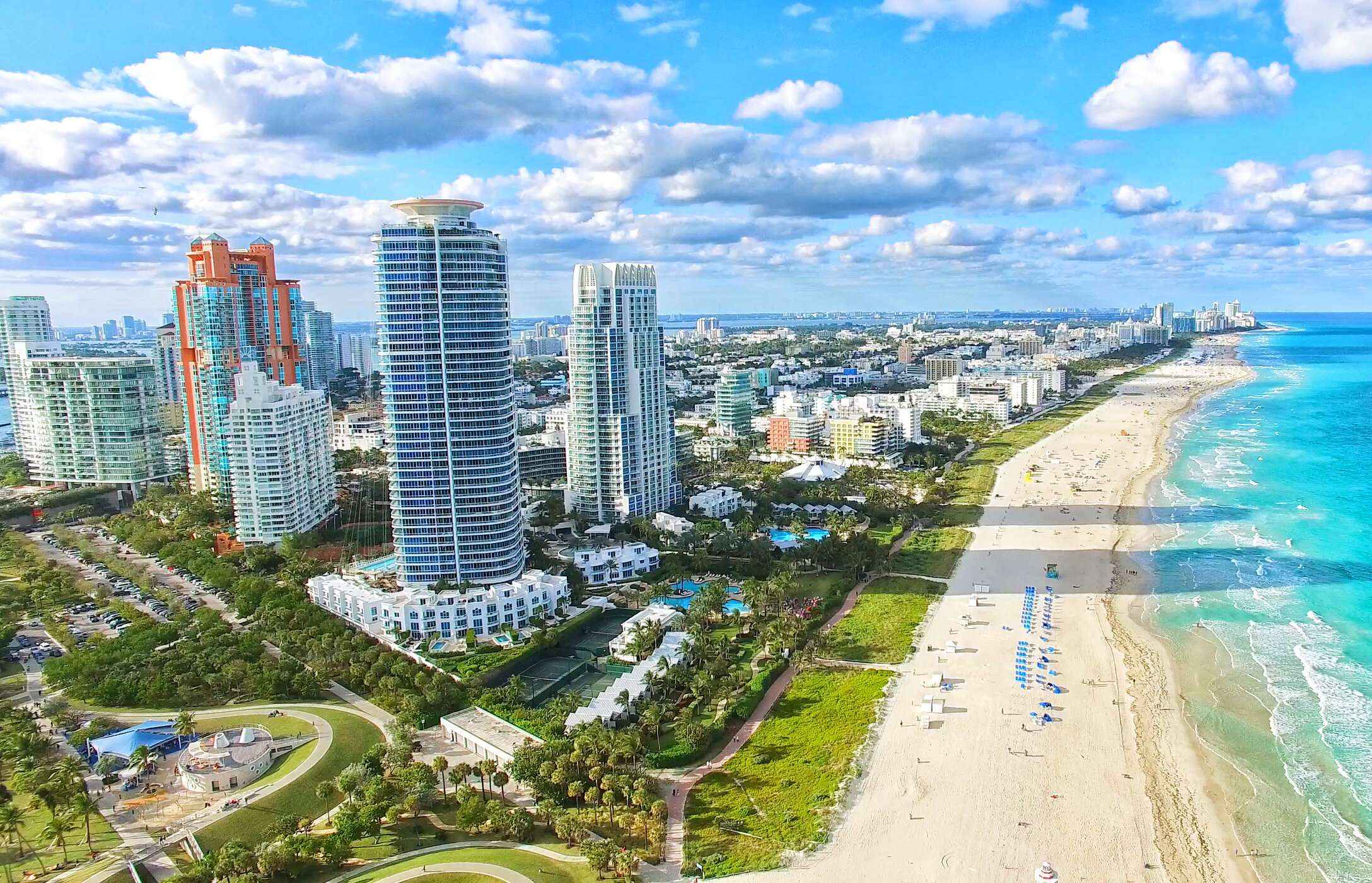 Blick über den weißen Sandstrand von South Beach, mit kristallklarem Wasser und hohen Gebäuden parallel zum Strand