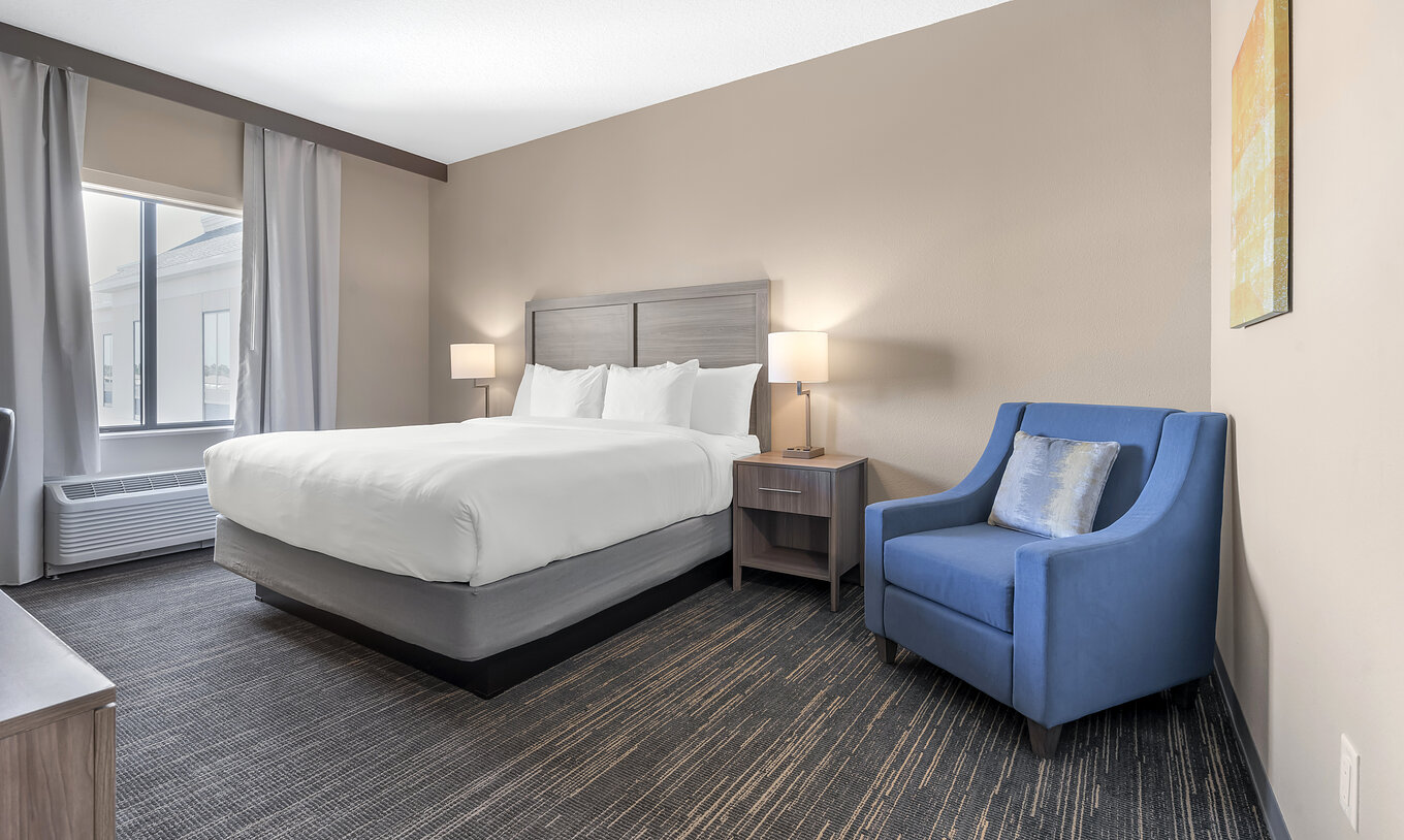 Das King-Zimmer im Pestana Orlando Suites Lake Buena Vista hat ein Doppelbett, Nachttisch und Sessel